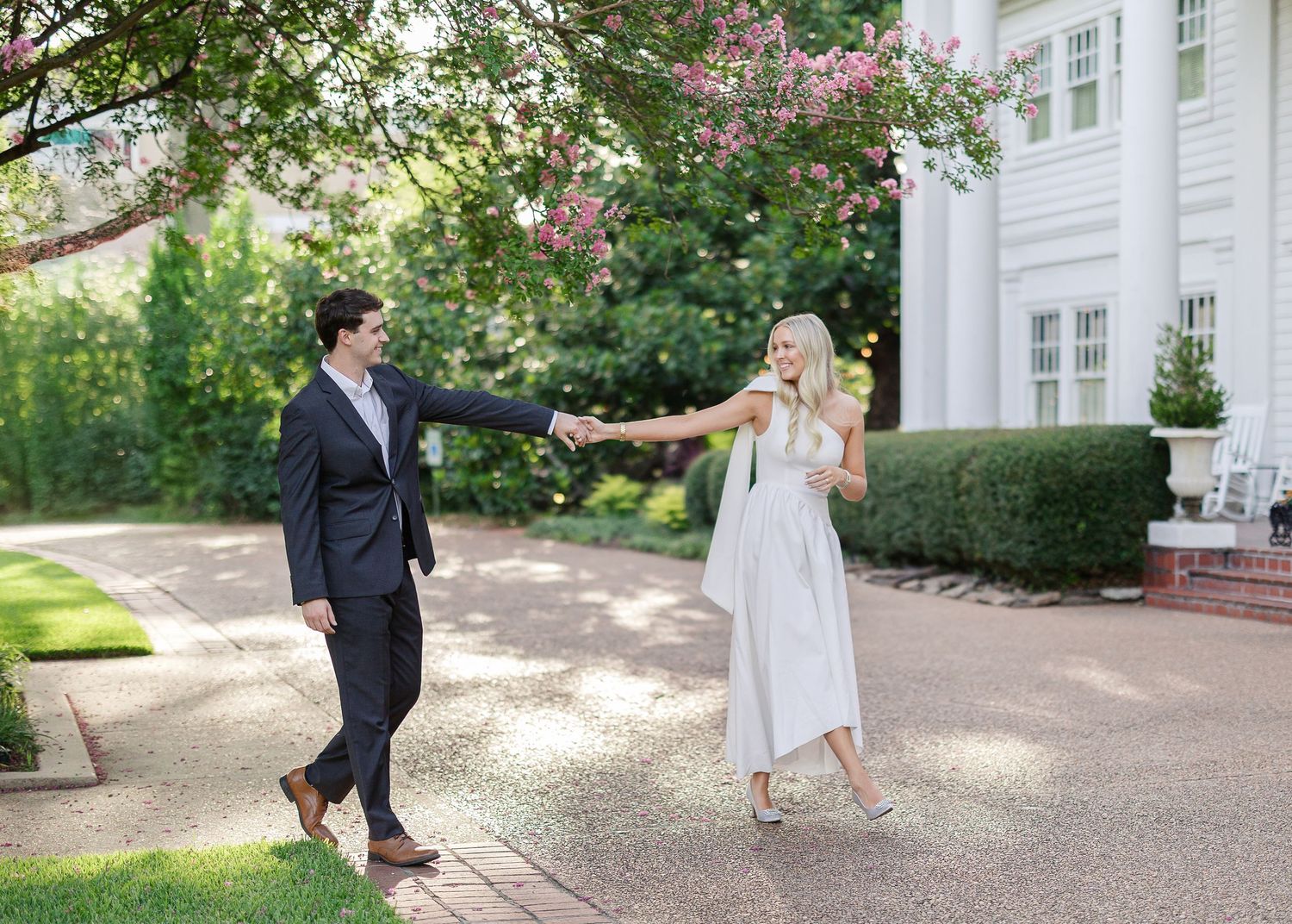 Classic white colonial architecture with brick walkway and manicured gardens.