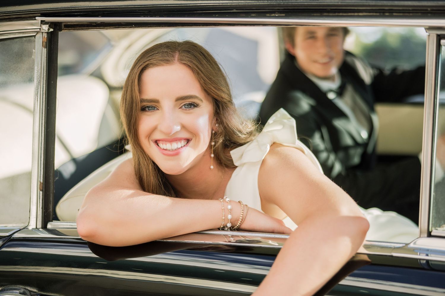 Happy couple in vintage car during golden hour photo shoot.