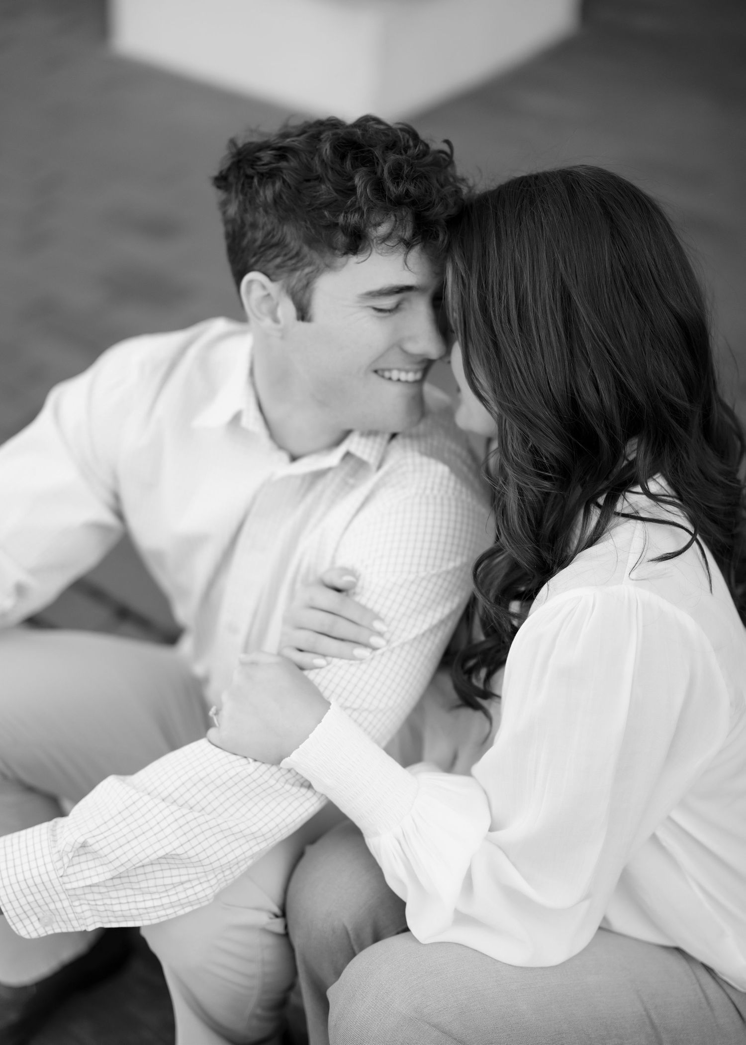 A black and white photo of a couple sharing an intimate moment while sitting close together.