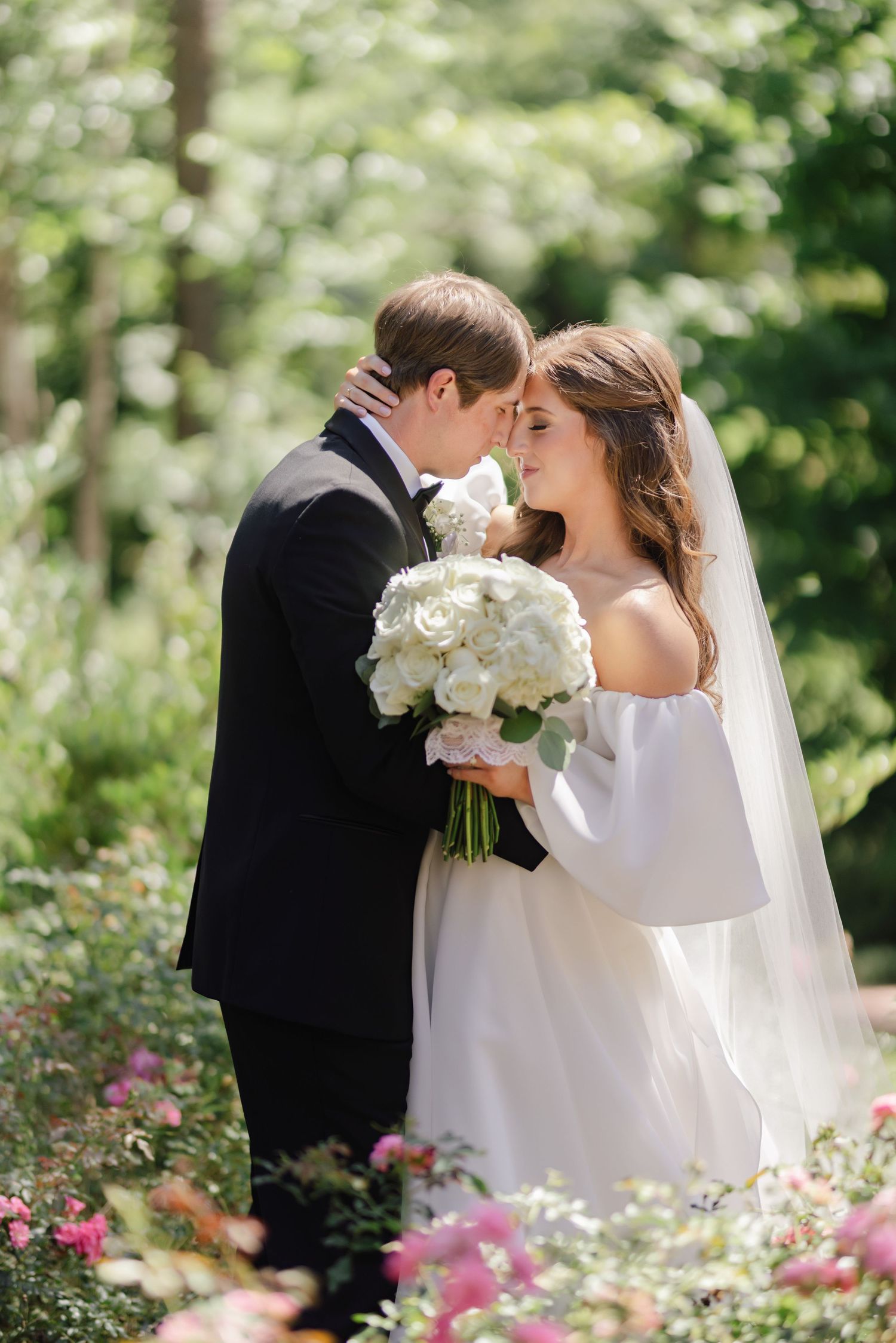 Intimate wedding moment with a couple sharing a tender moment surrounded by garden flowers.