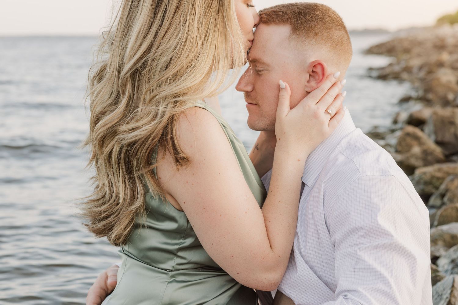 Romantic couple embraces near the ocean during sunset photoshoot.