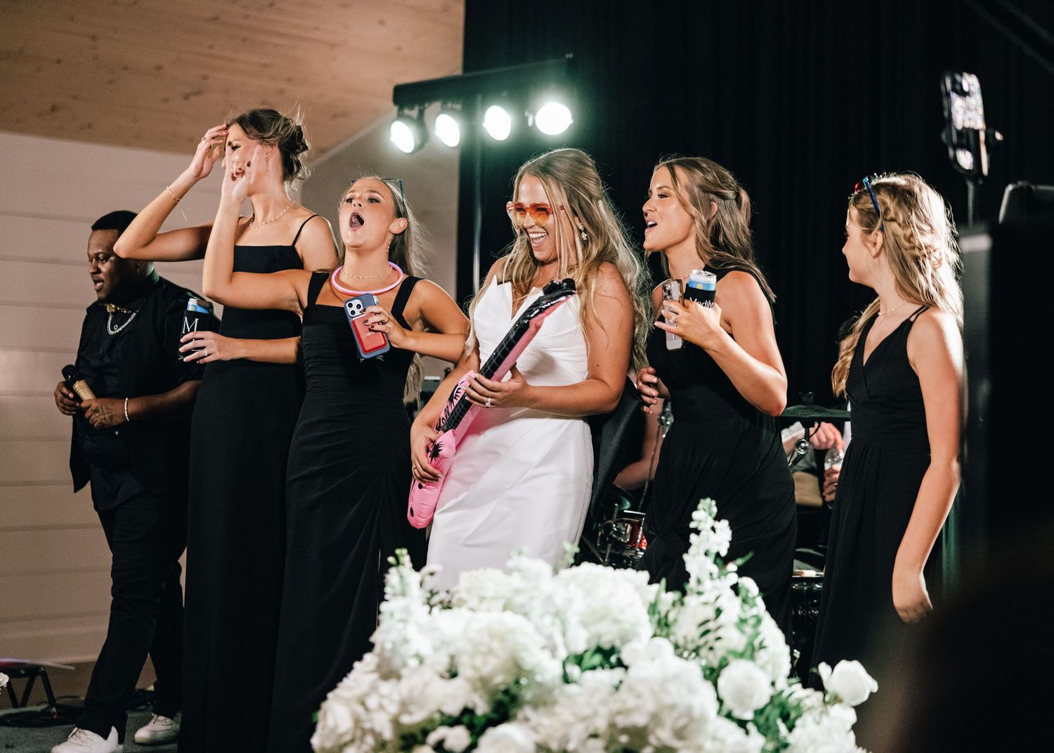 Wedding band performers in black dresses entertaining guests on stage with instruments.