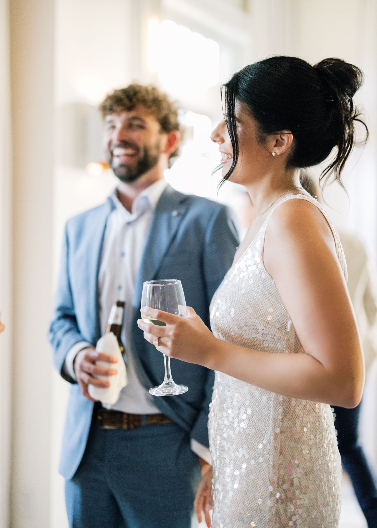 Wedding guests in formal attire holding champagne glasses during an elegant indoor reception celebration.