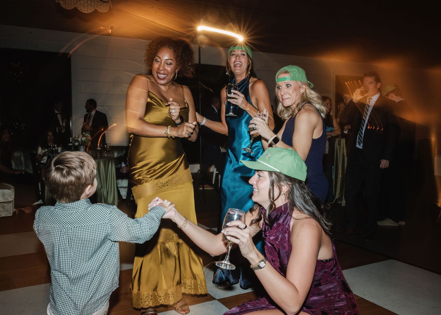 People dancing and celebrating at an indoor party with warm ambient lighting and festive atmosphere.