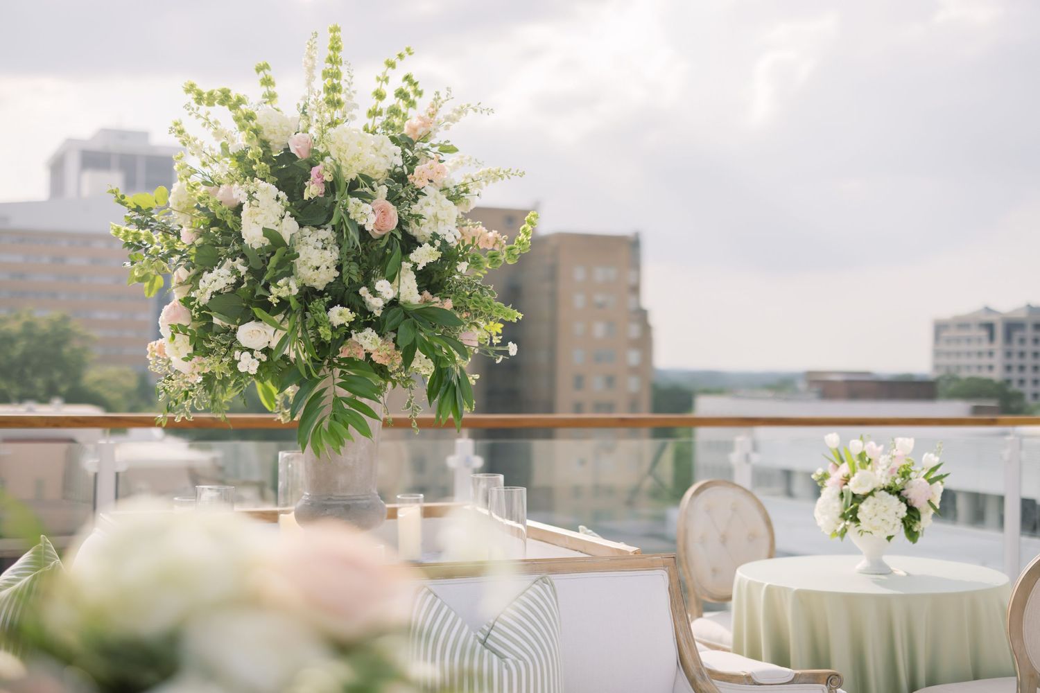 Elegant reception table setting with white floral centerpieces and green tablecloths in a modern venue.