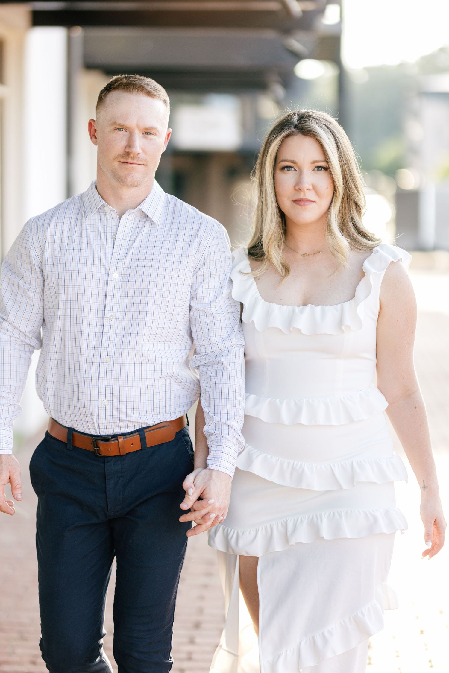 Couple in white and blue casual attire strolling together on a brick walkway.