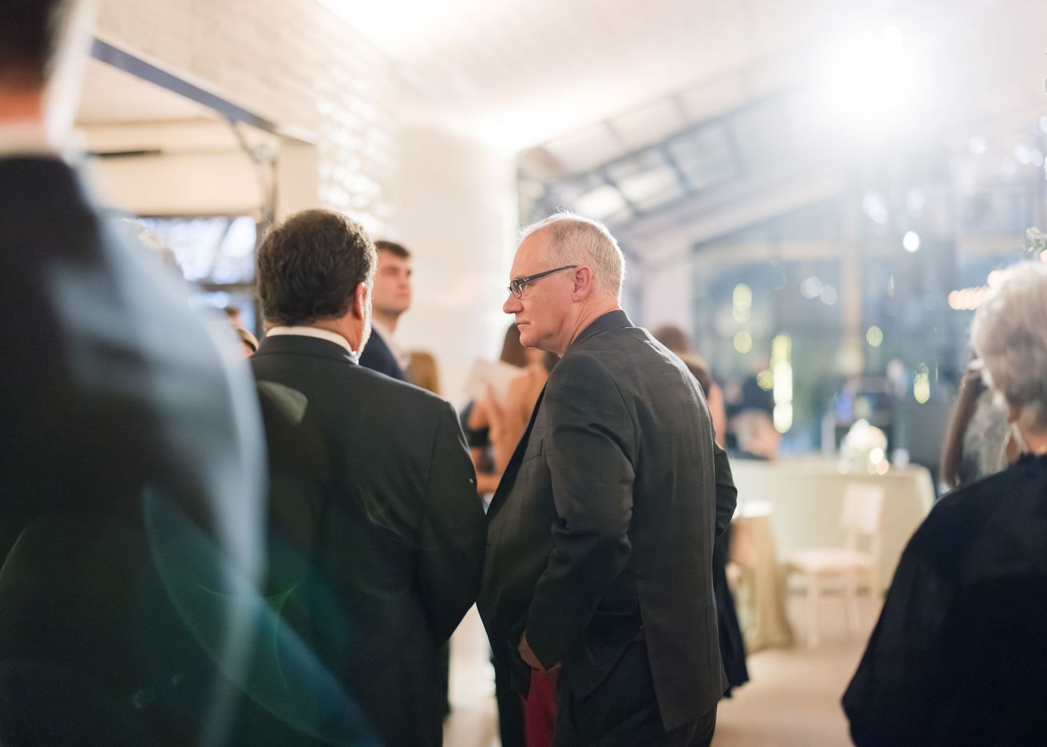A series of candid photos showing people in formal attire conversing at an indoor event or gathering.