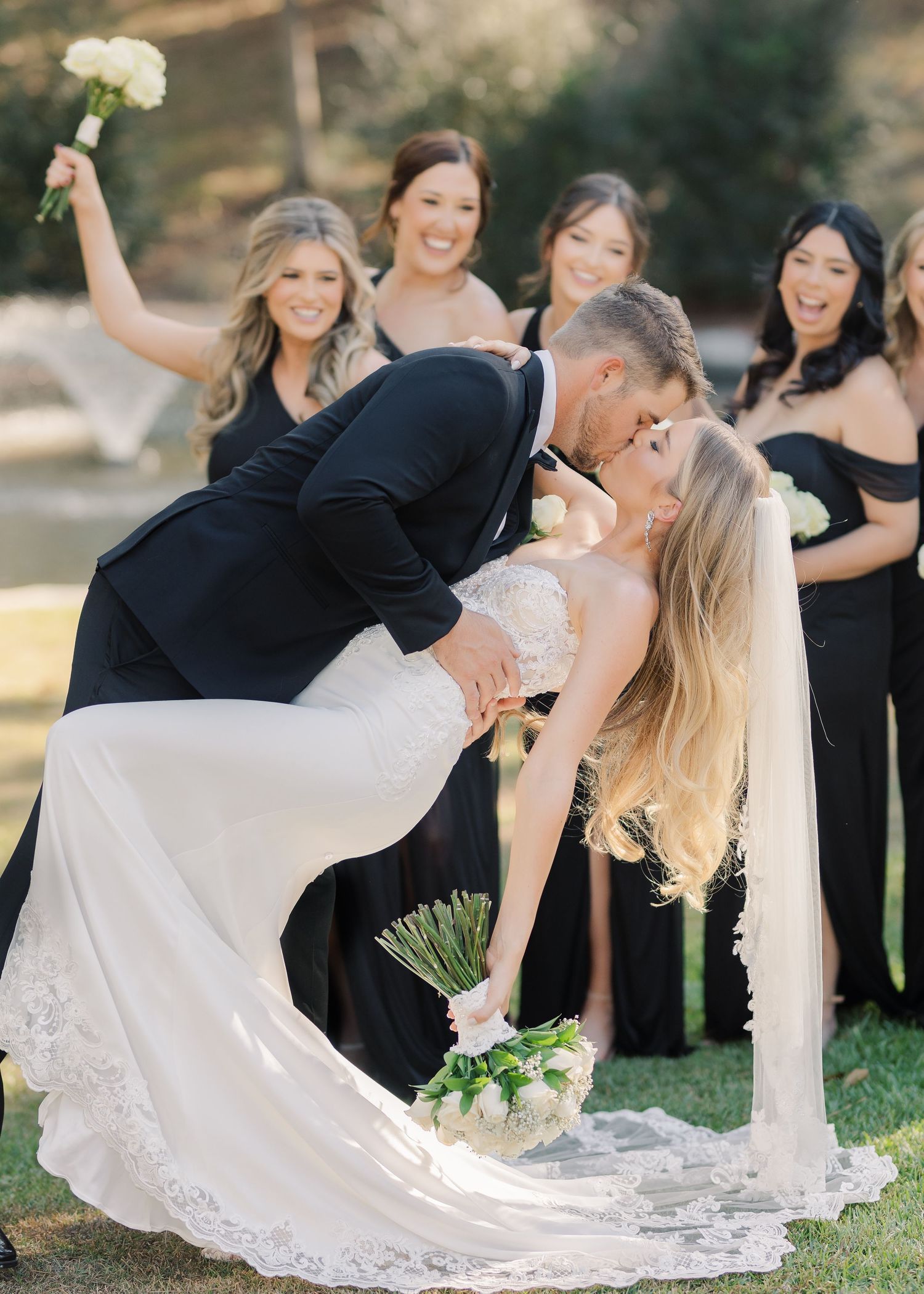 A five panel series of romantic dip poses in black and white wedding attire on an outdoor lawn at sunset.