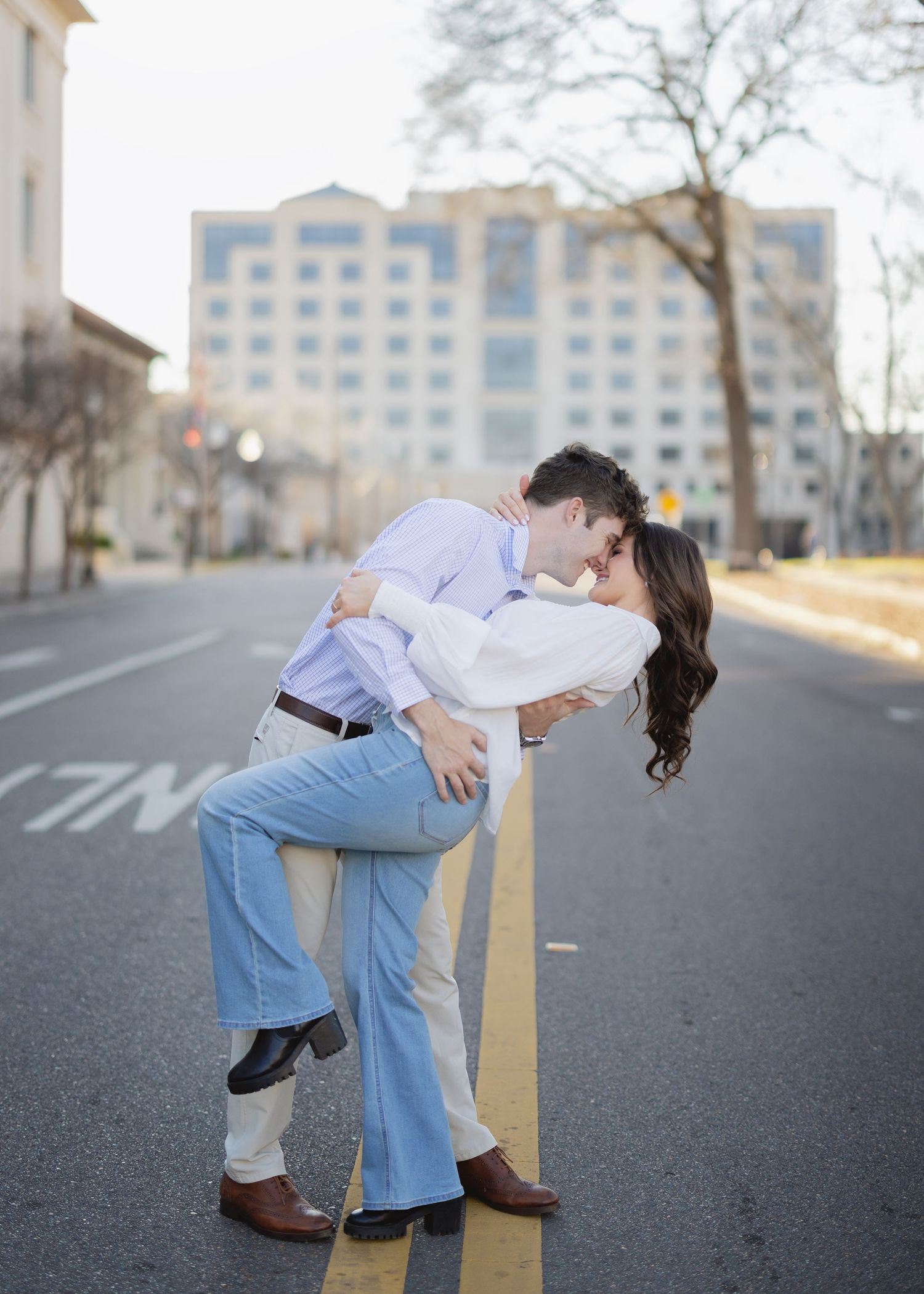 A romantic dip kiss between a couple on an urban street.
