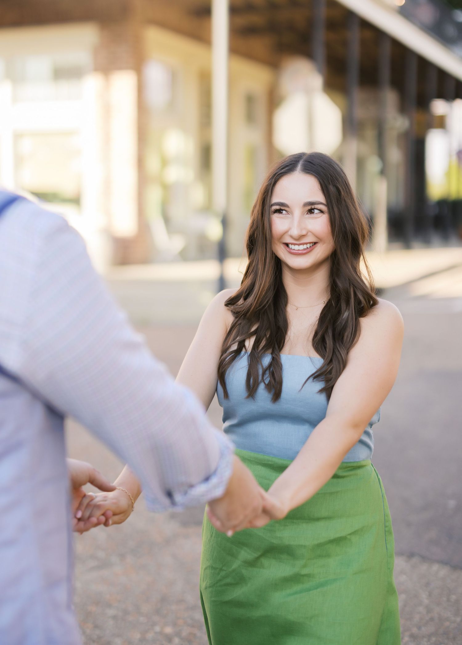 A person in a blue top and green skirt poses outdoors in a series of candid shots showing natural expressions.
