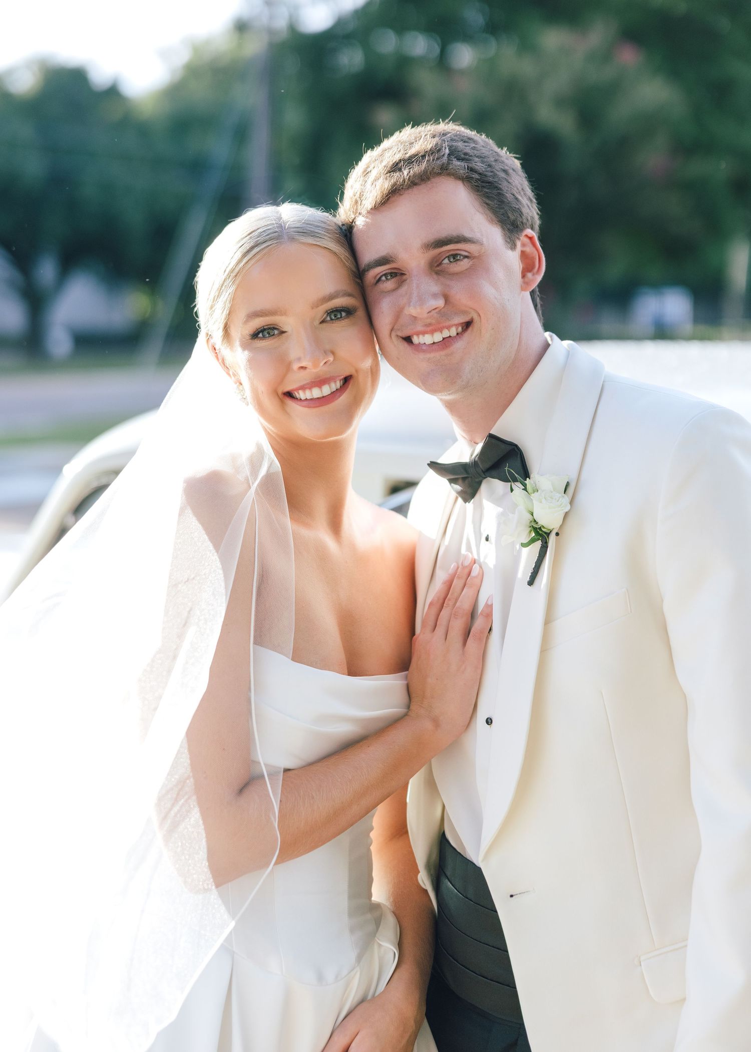 Newlyweds embrace in formal white attire for romantic wedding portrait.