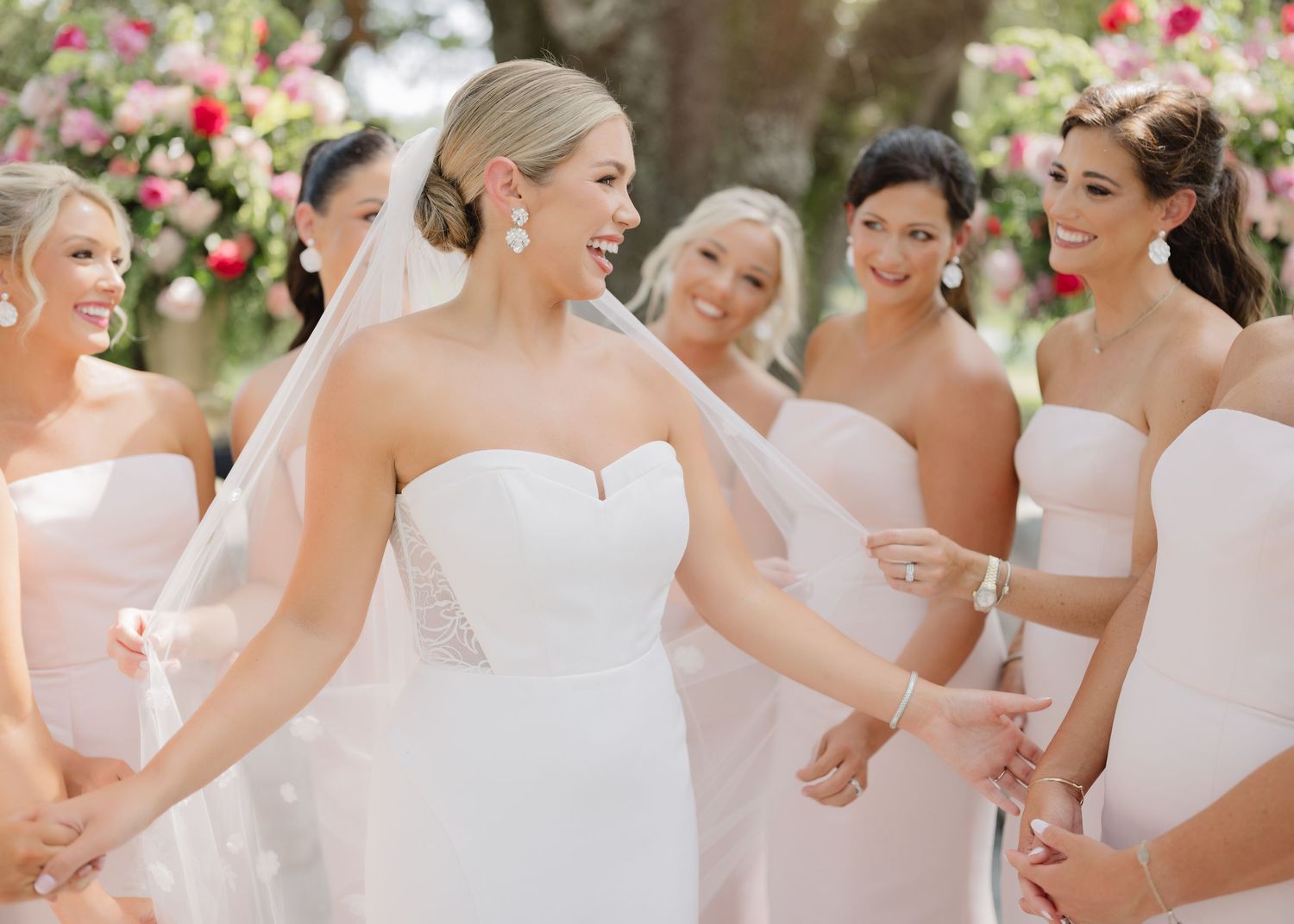 Bridesmaids in white dresses posing together outdoors.