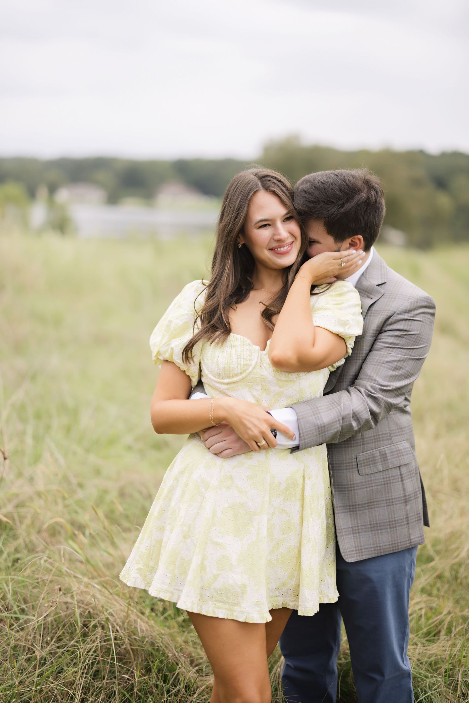A couple sharing a tender moment in a grassy field with casual attire.