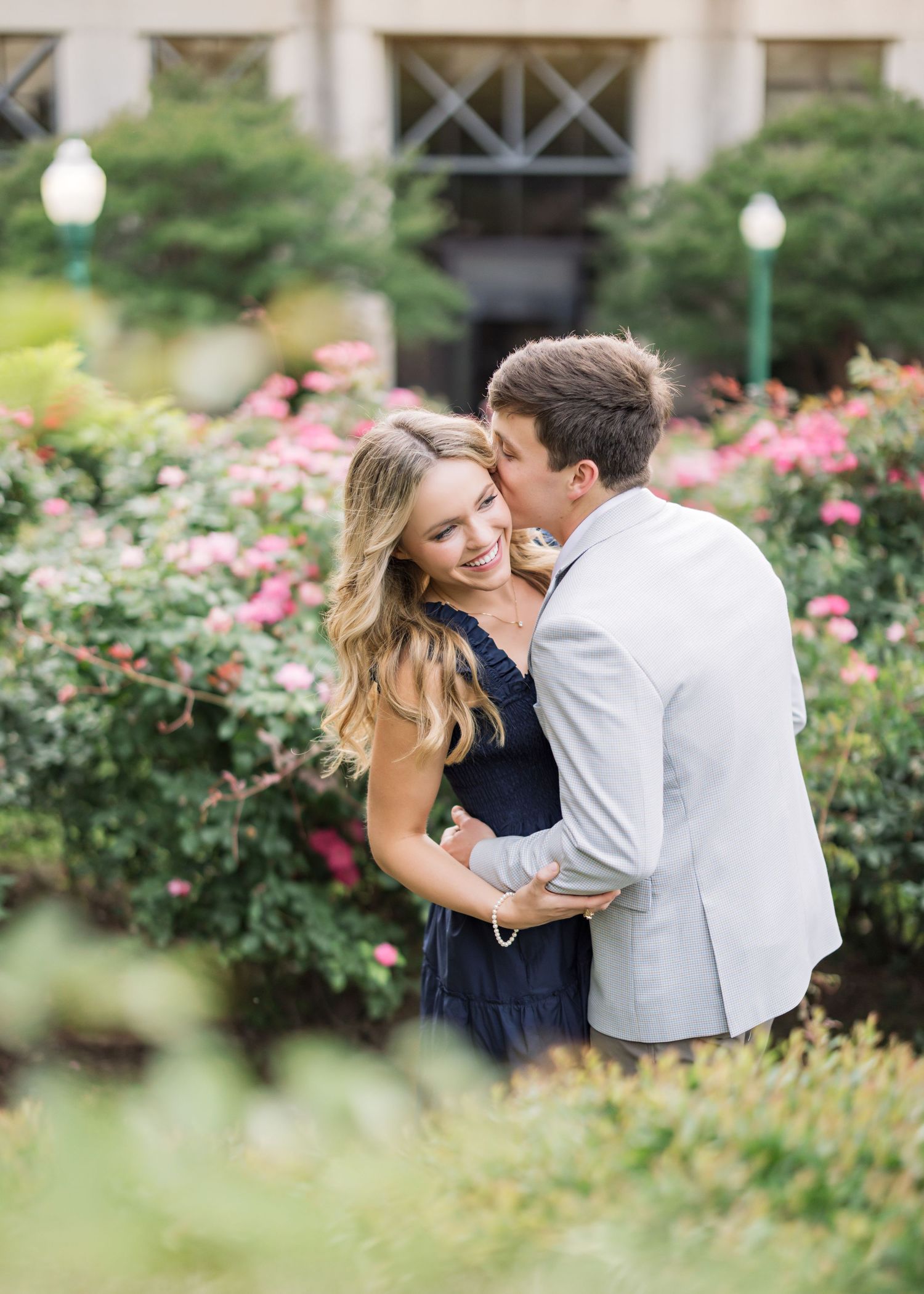 Romantic couple photos in blooming rose garden with pink flowers.