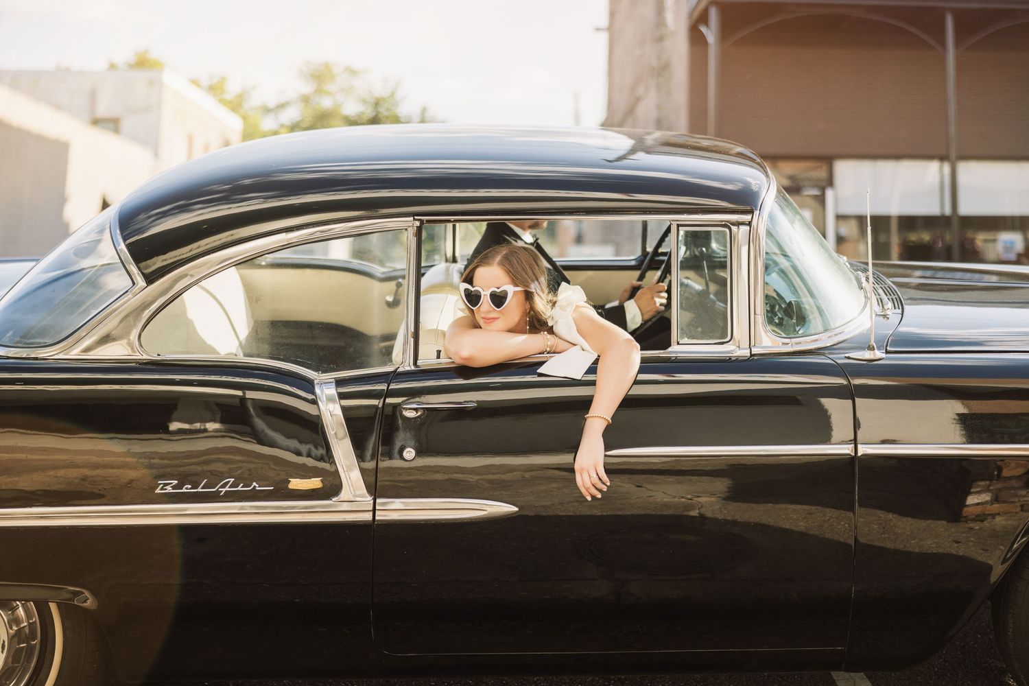 Creative photo series featuring poses with a vintage black car.