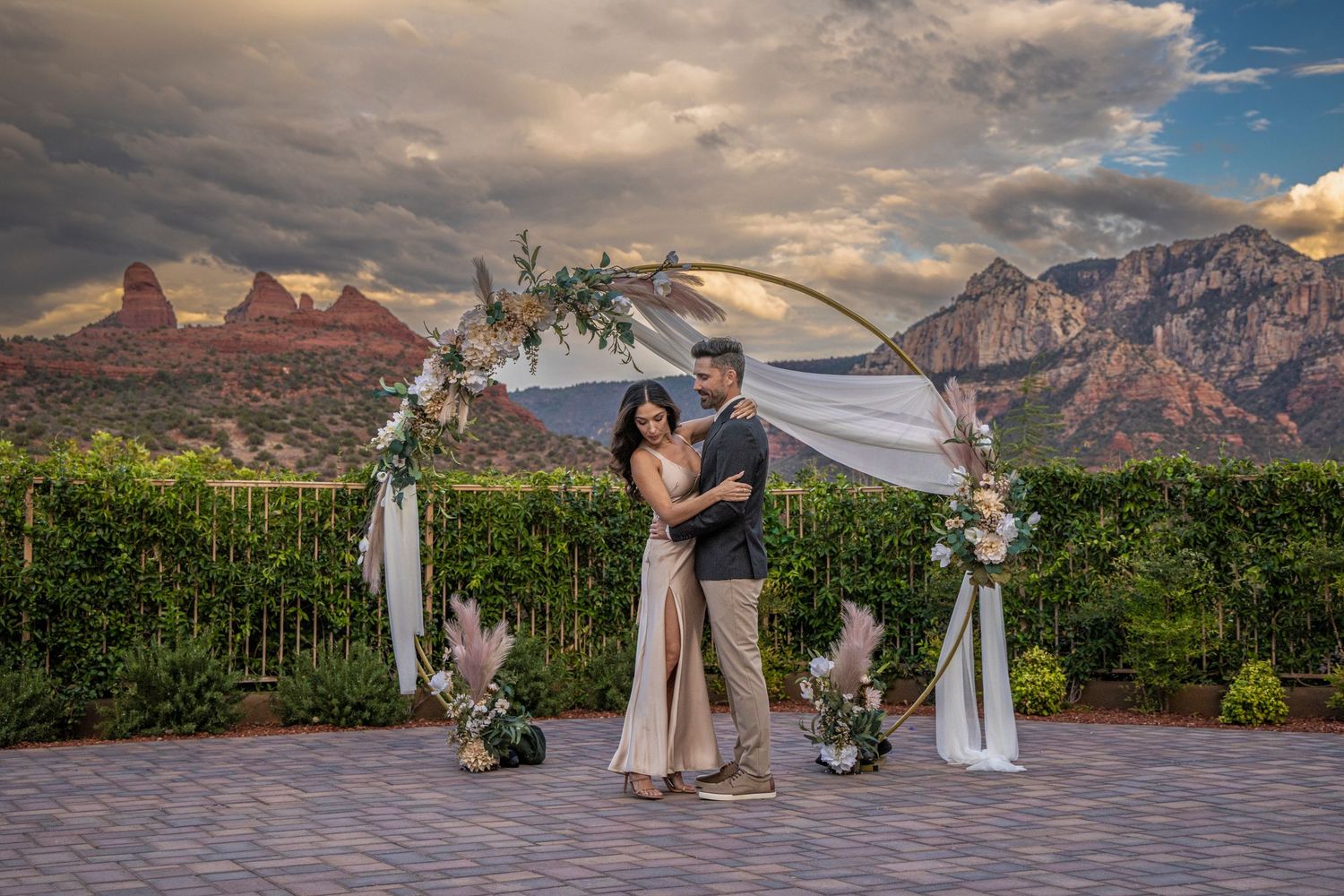A stunning outdoor wedding ceremony with dramatic mountain peaks and red rock formations in the background.