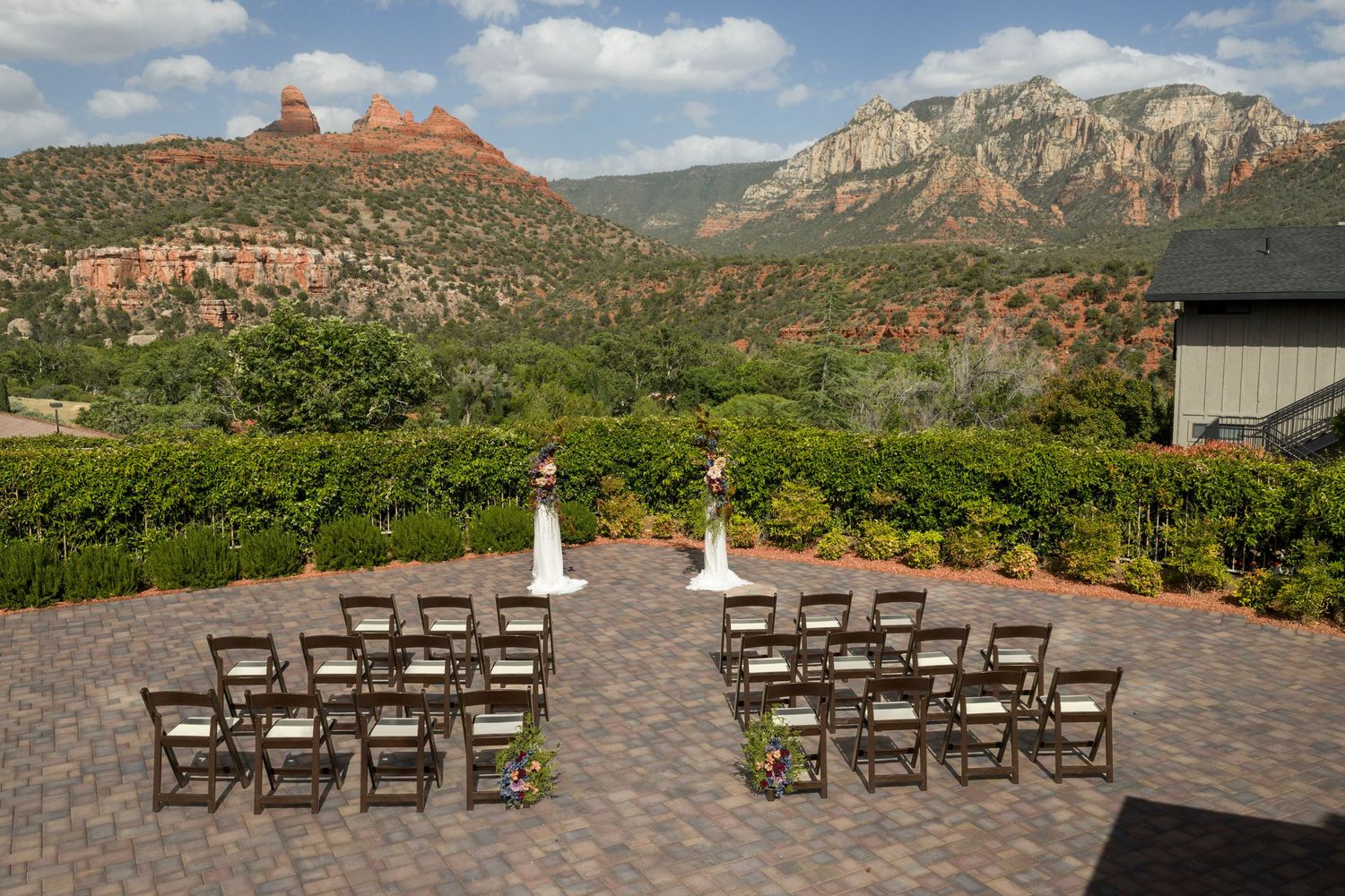 Outdoor wedding ceremony setup on a patio with red rock mountains and lush greenery in Sedona, Arizona.