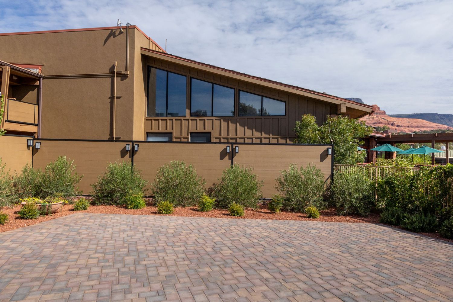 A series of paver walkways and patios surround a desert-style building with mountain views in the background.