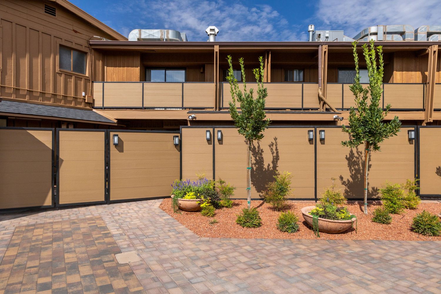 A series of connected paver patios with desert landscaping and tan stucco walls creates an outdoor living space.