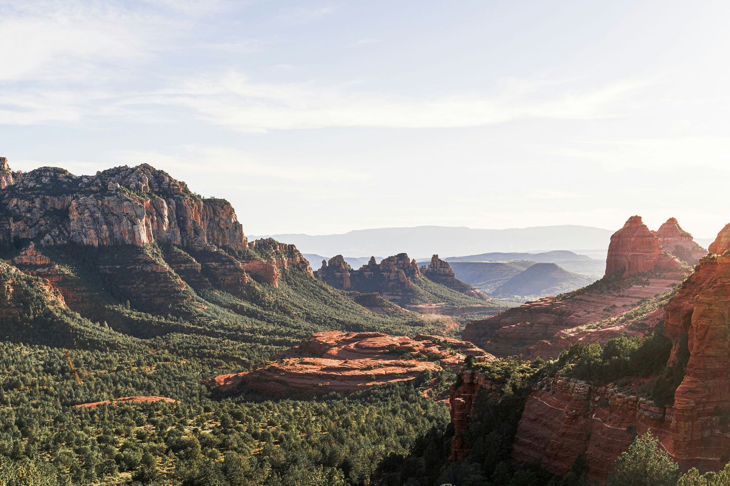 Aerial view of Sedona Arizona red rock formations and lush green valley landscape at golden hour.