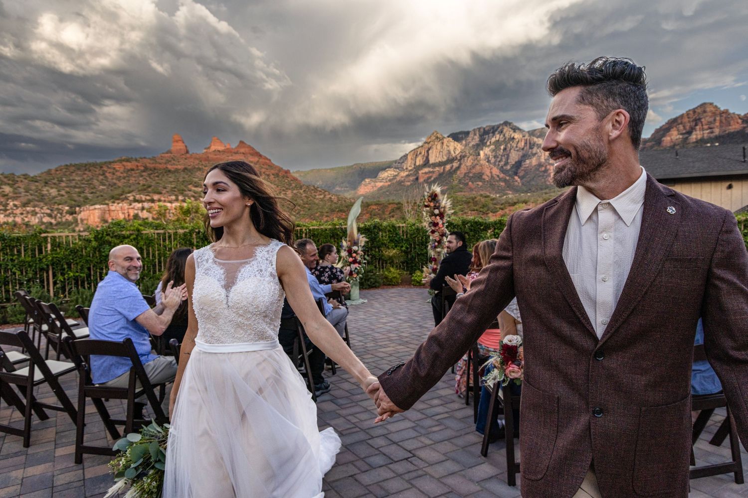A wedding couple dances together during sunset at a scenic outdoor venue with mountains in the background.