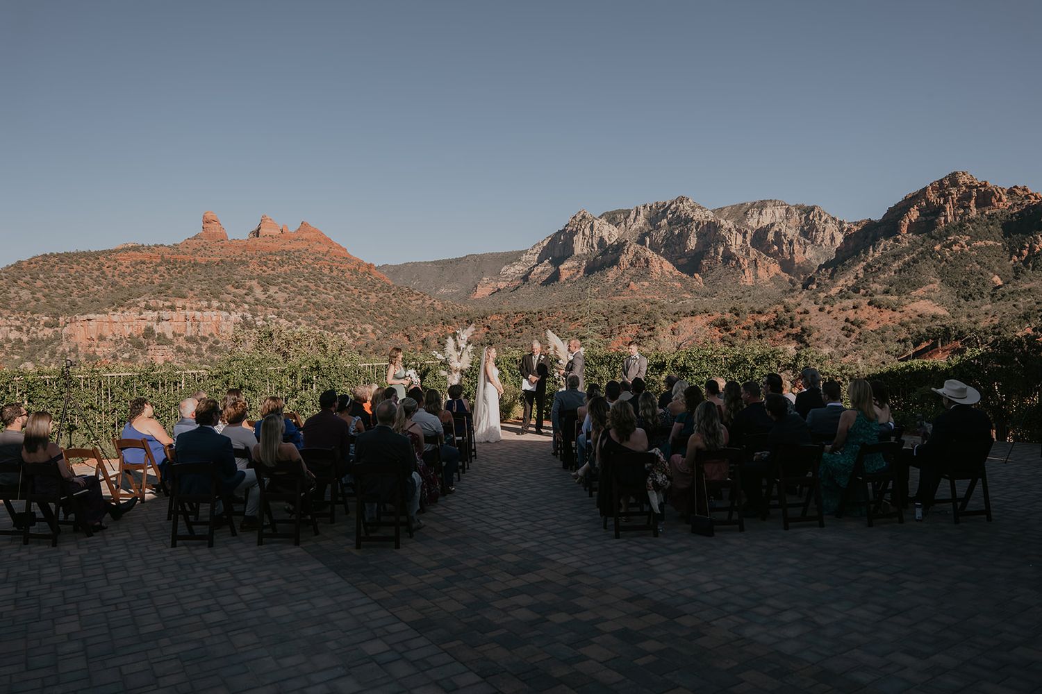 Outdoor wedding ceremony in Sedona Arizona vineyard with stunning red rock mountain backdrop and seated guests.