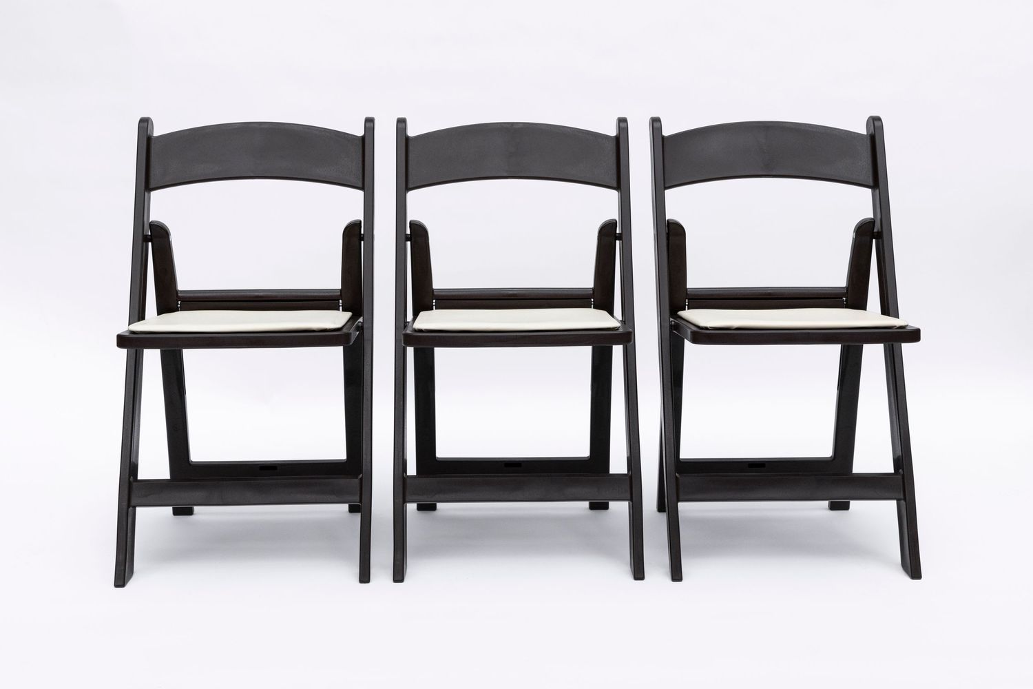 Three black wooden folding chairs arranged in studio product photography.