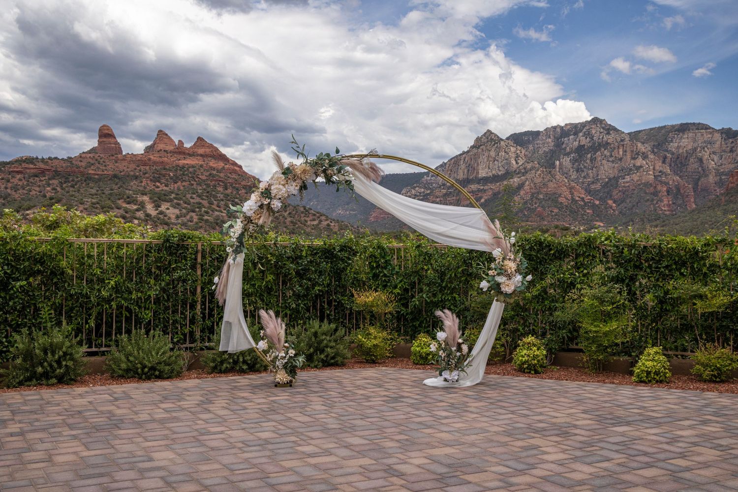 Wedding arch decorated with white fabric and flowers against Sedona's red rock landscape.
