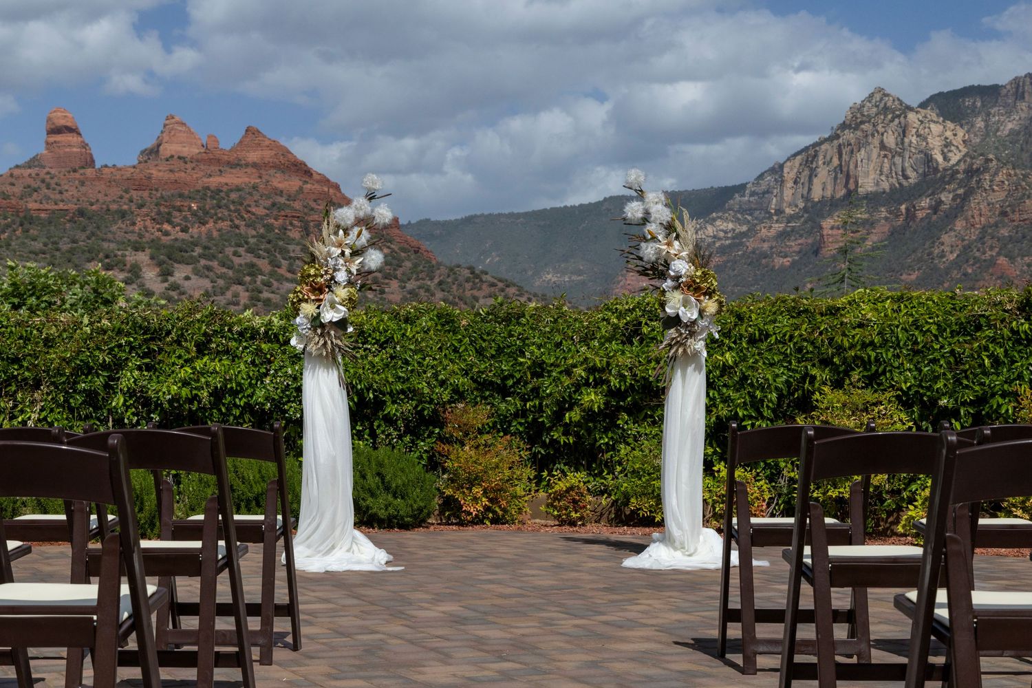 Outdoor wedding ceremony setup with floral columns and stunning red rock Sedona Arizona mountain backdrop.