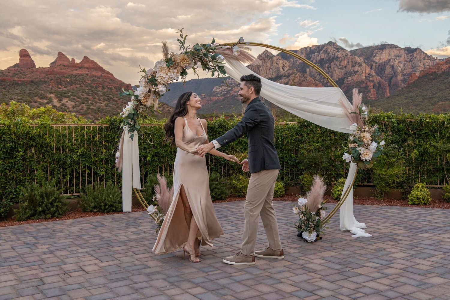 A couple shares an intimate moment during their outdoor wedding ceremony with desert mountains in the background.