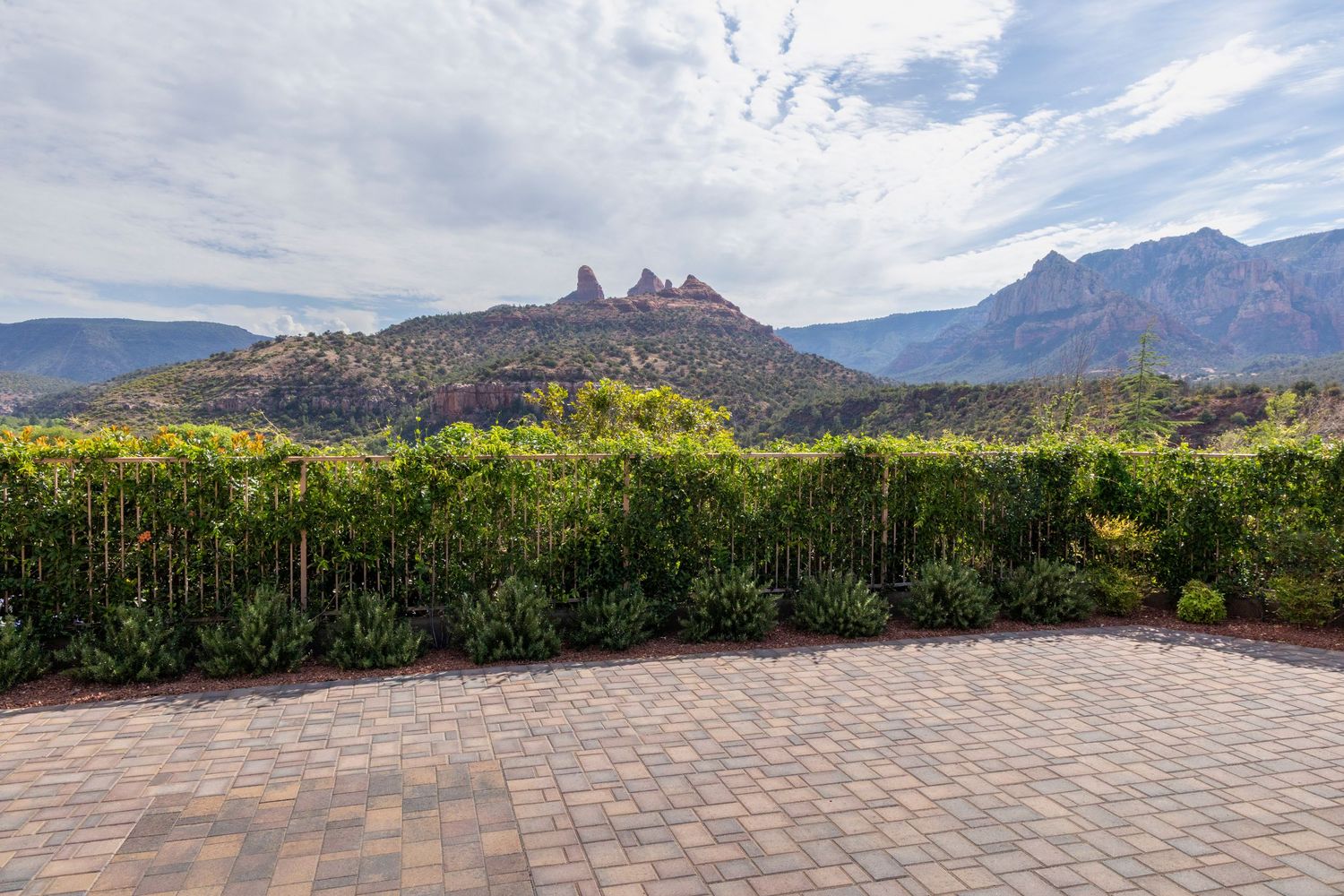 Paved stone patio overlooking scenic red rock formations and mountains in Sedona with desert vegetation in foreground.