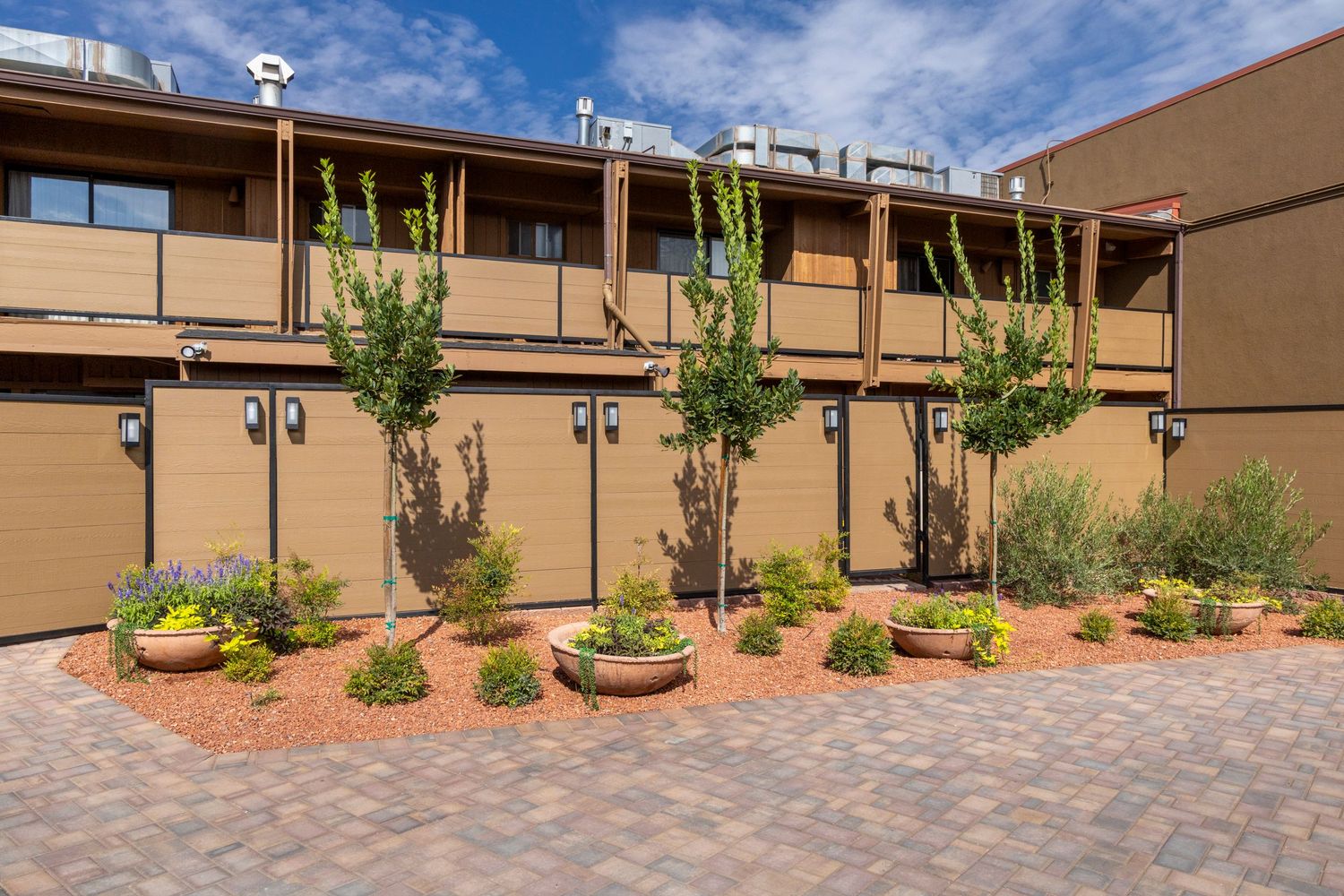 Panoramic view of a tan commercial building with desert landscaping and paved walkway under bright blue skies.