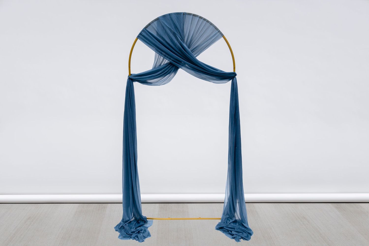 Elegant navy blue draped fabric arch against white background for wedding ceremony setup.