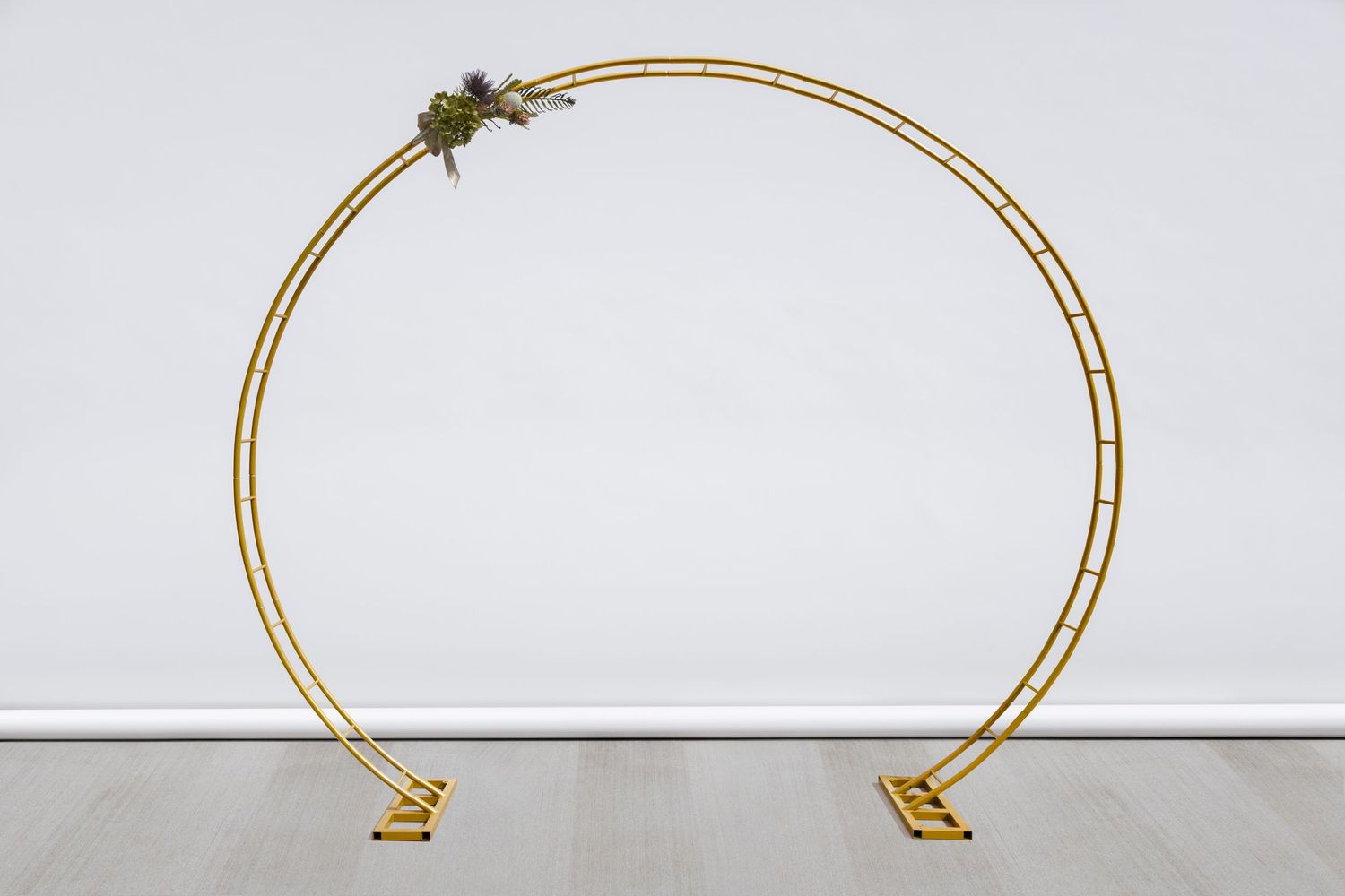 Modern circular gold wedding arch against white background.