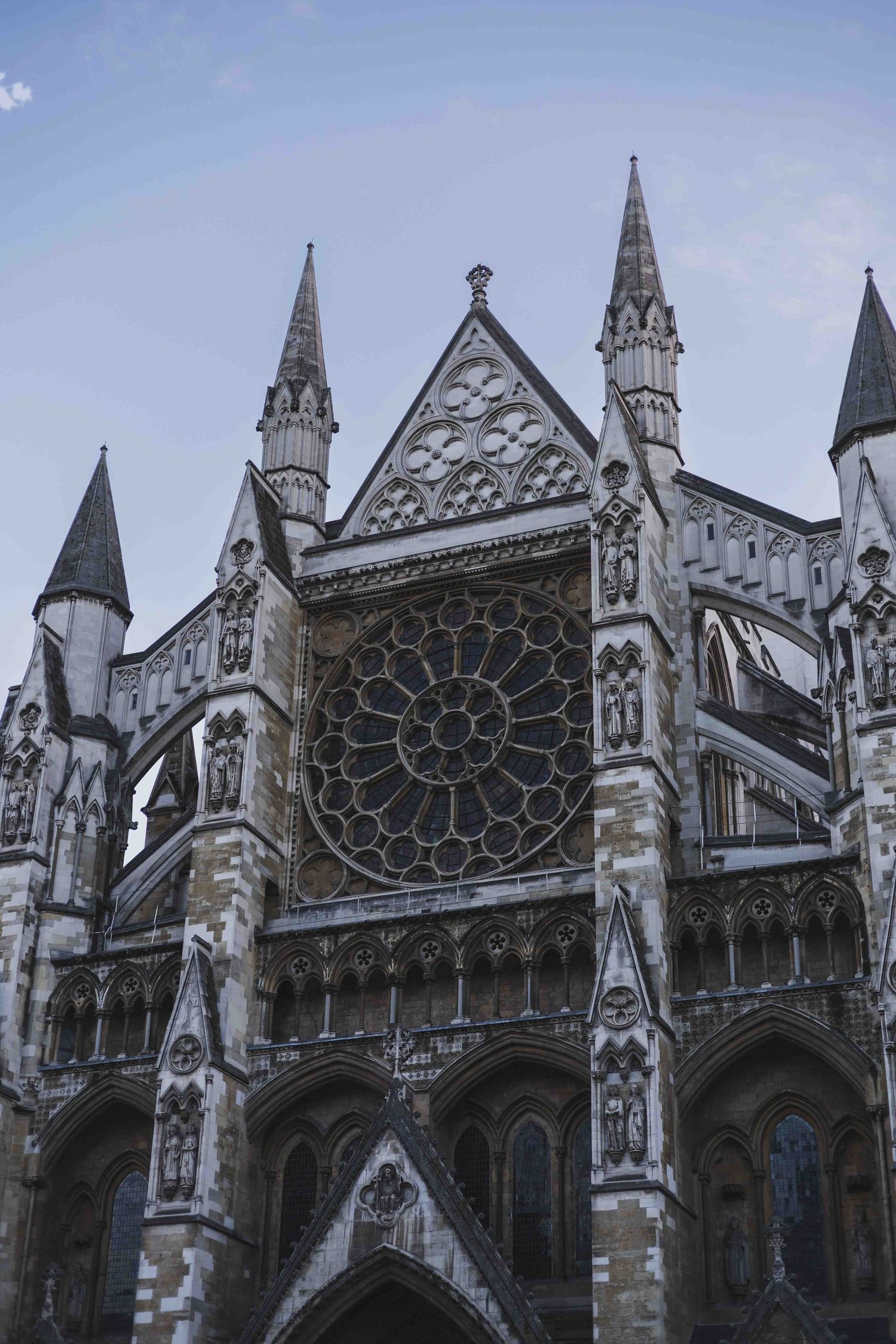 Gothic cathedral exterior details showing ornate spires, flying buttresses, and a large rose window with intricate stone carvings.