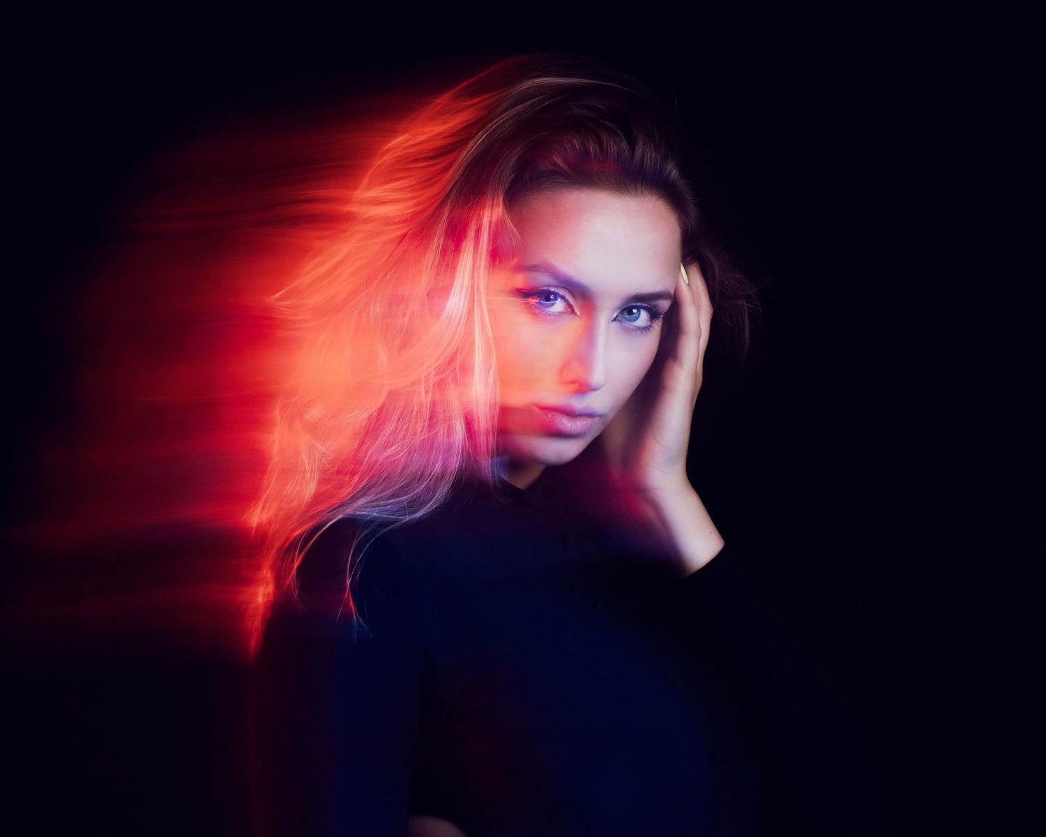 Artistic portrait with red and blue lighting creating dramatic motion blur effect.