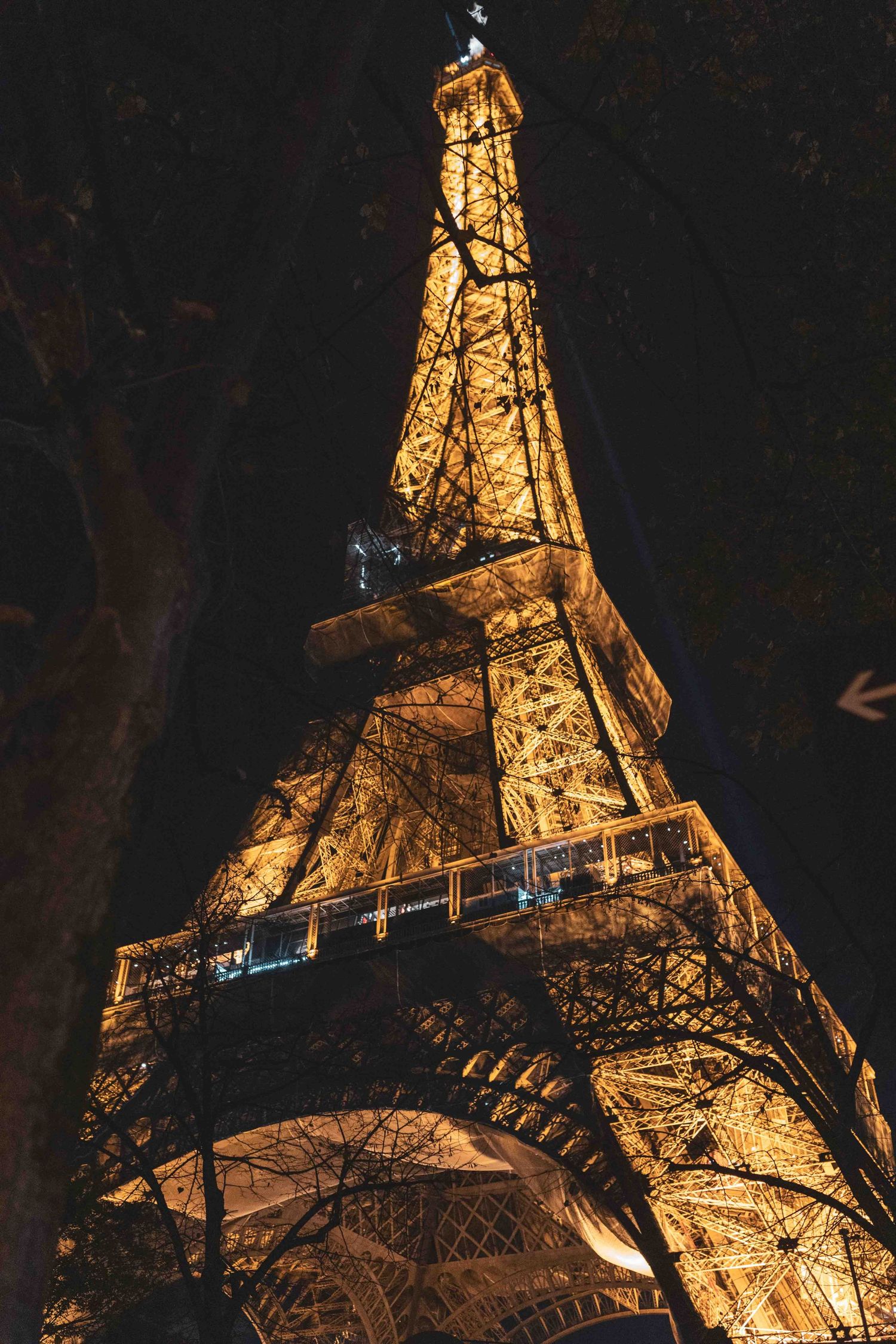 The iconic Eiffel Tower illuminated at night with warm golden lights against a dark sky in Paris, France.