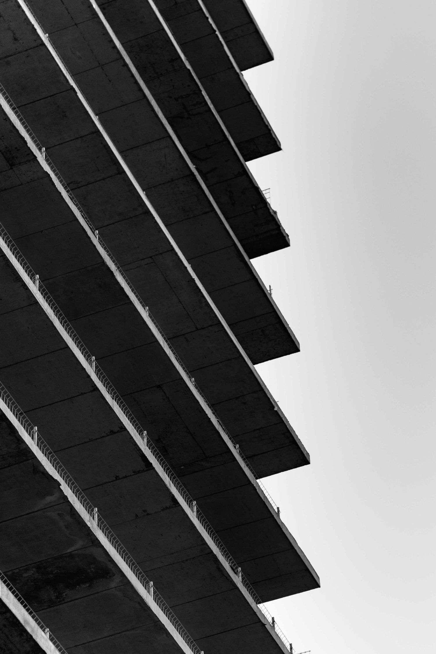 Angular black slats create geometric shadow patterns against a bright white background in minimalist architectural detail.