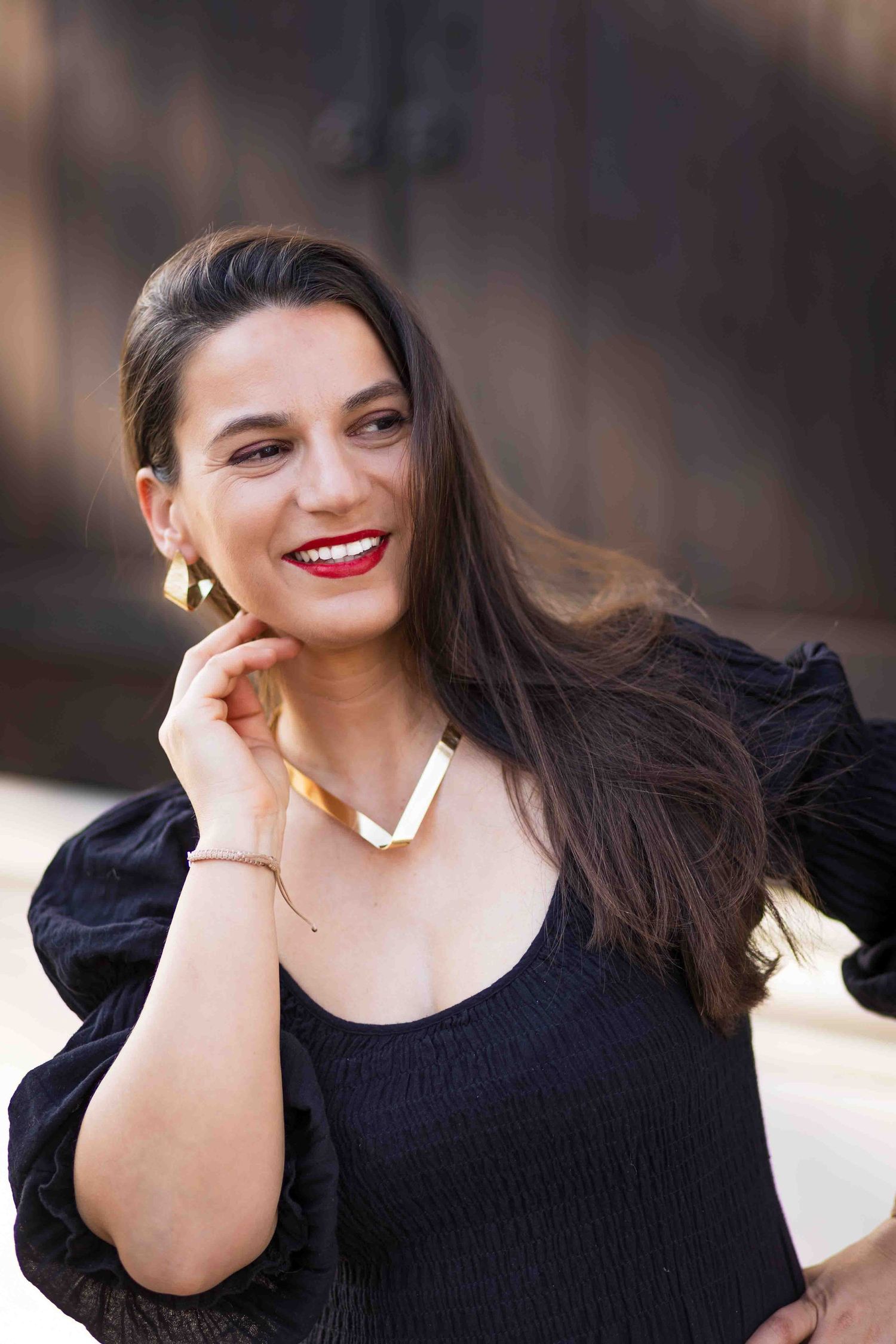 A series of artistic portraits featuring someone in a black outfit with flowing dark hair against a blurred background.