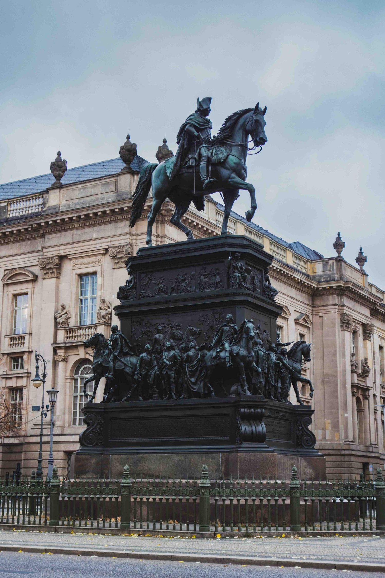 Historic equestrian monument statue with ornate base and classical building architecture in the background.