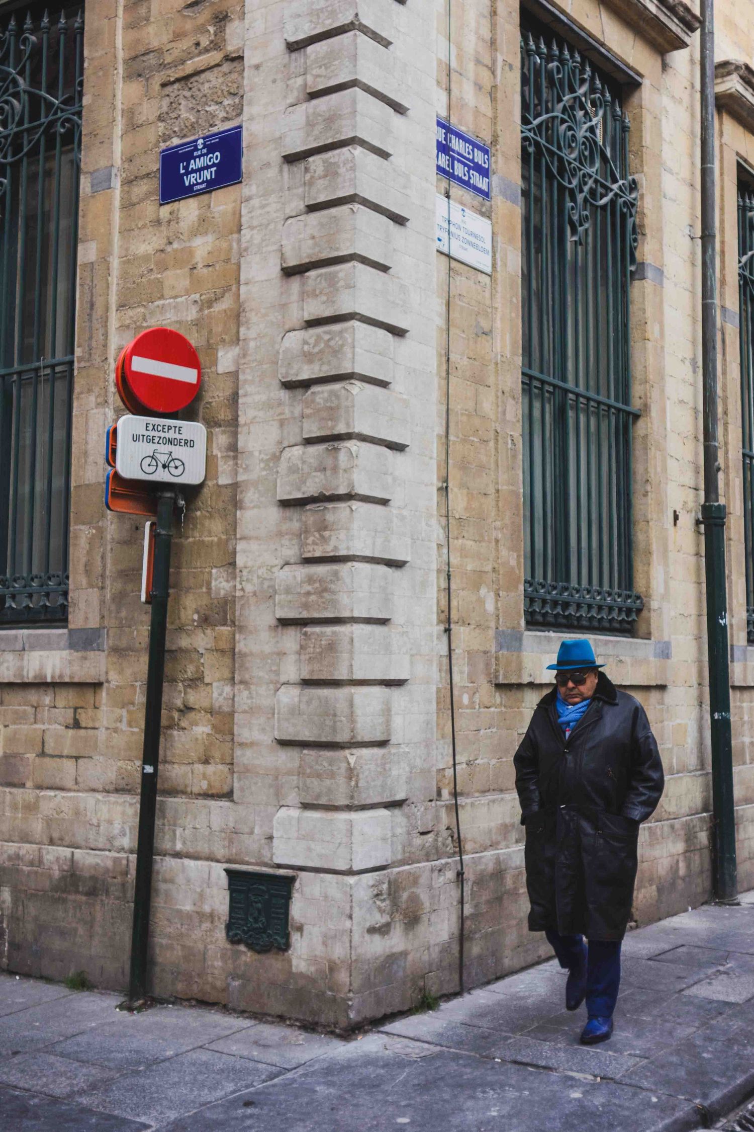 A street corner in a historic European district with stone architecture and street signs in French.