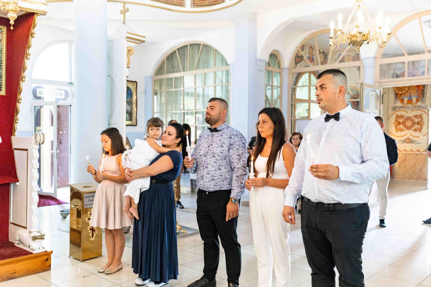 A series of individuals dancing and laughing in an elegant ballroom with ornate architectural details and white decor.
