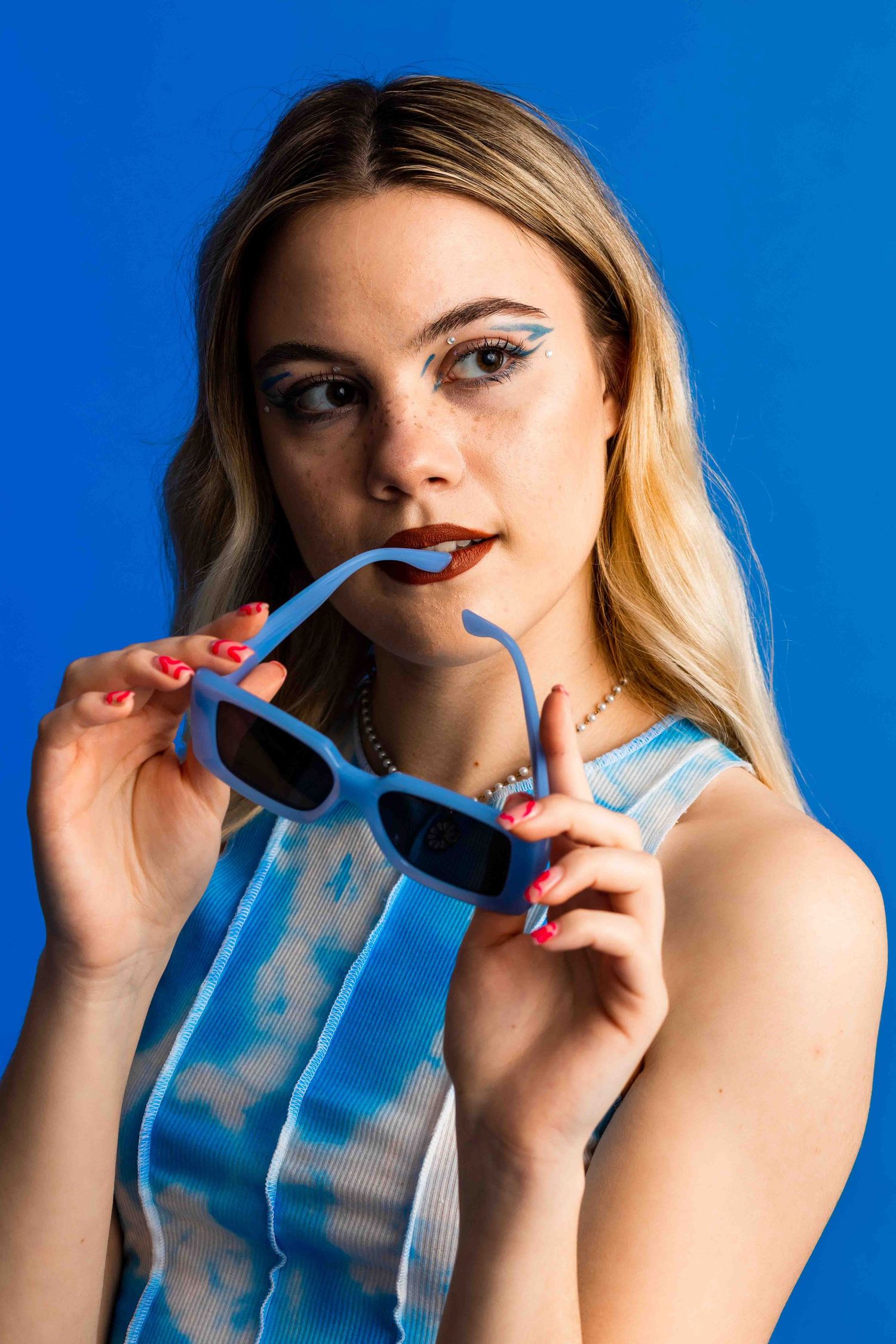 Sequence showing a person drinking blue liquid from a clear glass with exaggerated expressions against vibrant blue background.