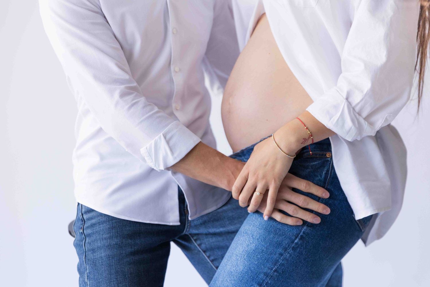 Person in white shirt and jeans holding their hip area in apparent discomfort or pain.
