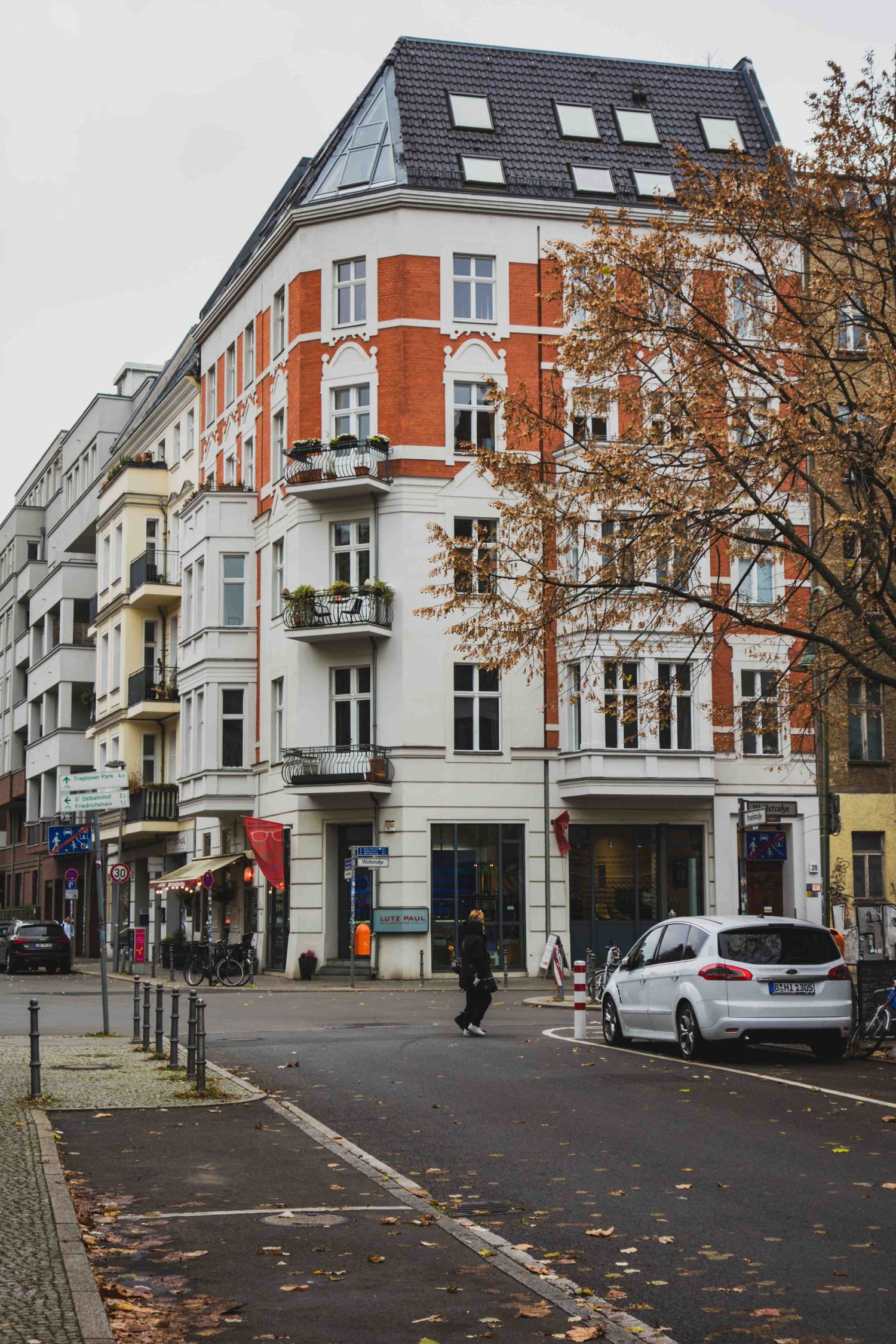 Corner building with classic European architecture in red brick and white trim stands at an intersection on a quiet street.