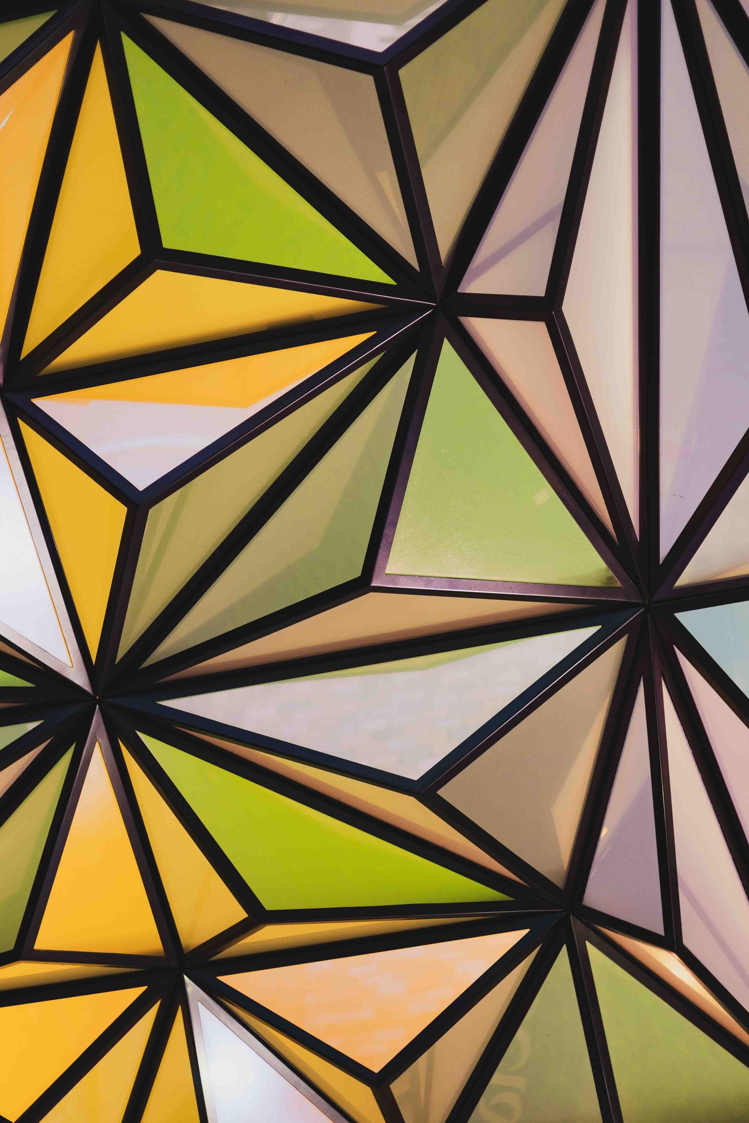 Abstract geometric pattern of black lines creating triangular shapes with yellow, green and white colored sections.