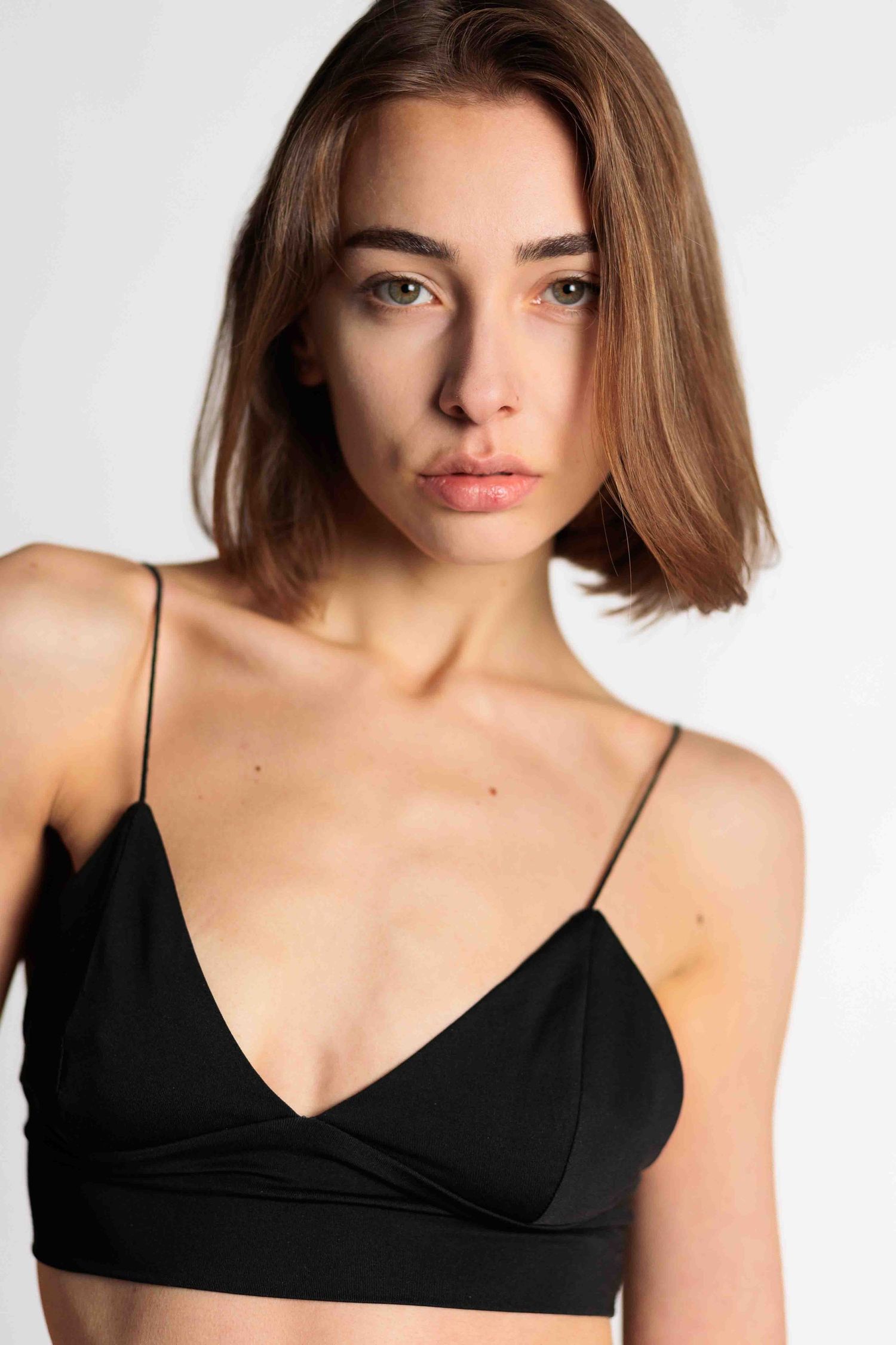 Four similar portrait shots showing a black bralette worn against a light neutral background.