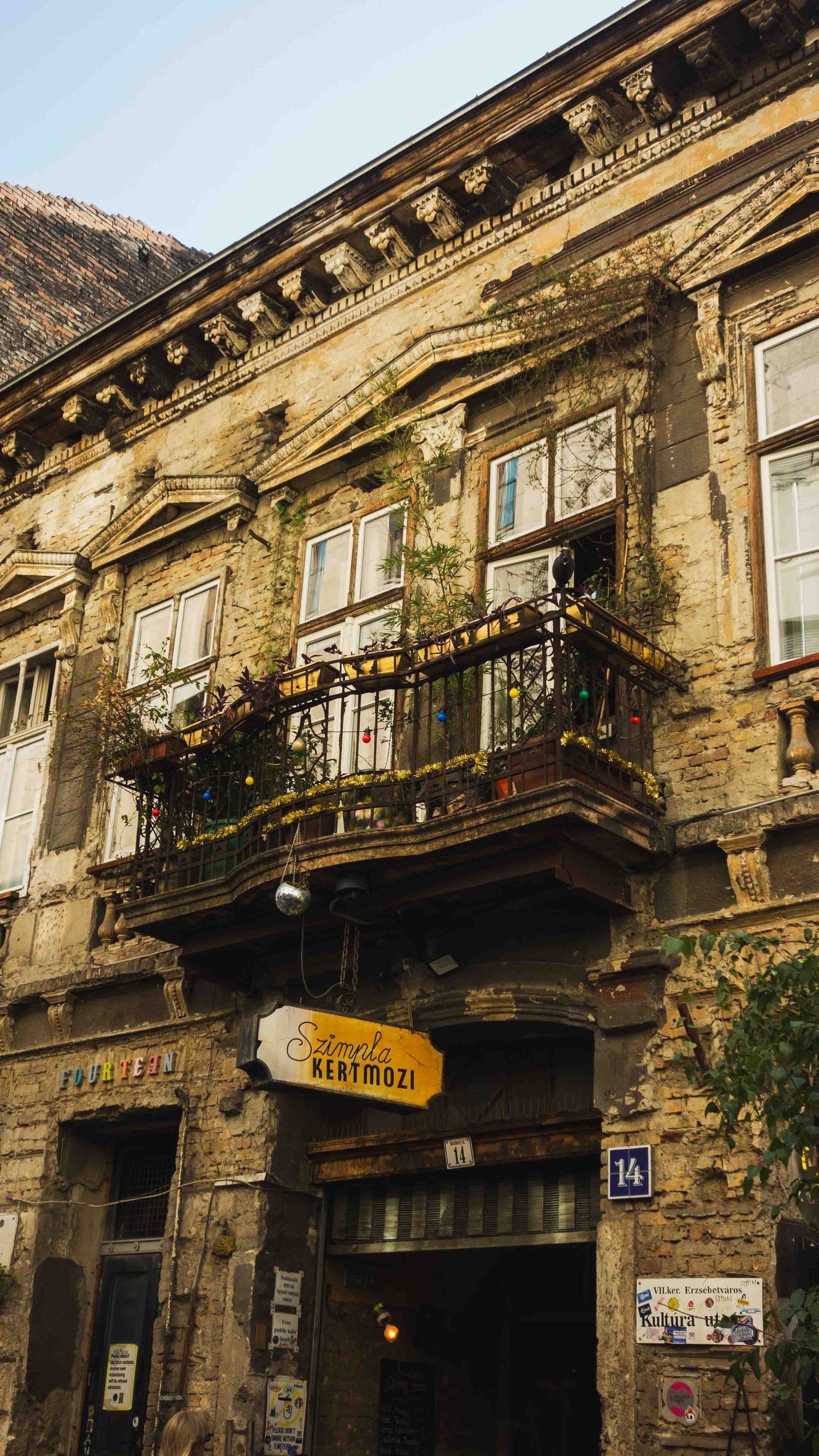 Weathered historic building facade with ornate architectural details and balconies in an old European city district.