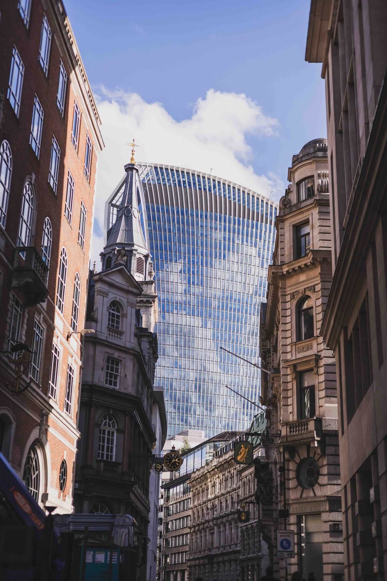 Modern glass skyscraper 'The Walkie Talkie' contrasts with historic architecture in London's financial district.