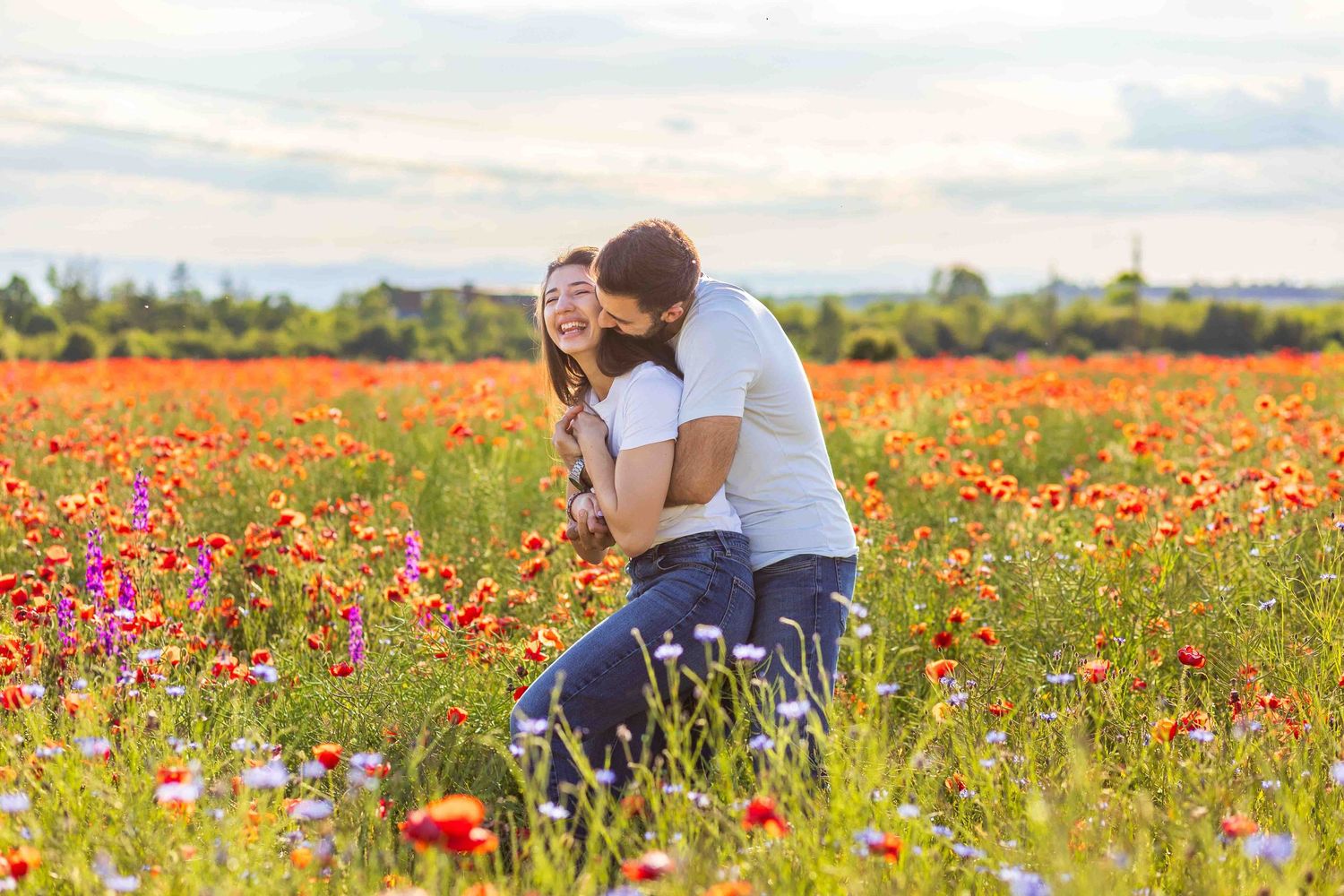 Someone stands in a vibrant field of red poppies and wildflowers during a sunny afternoon in summer.